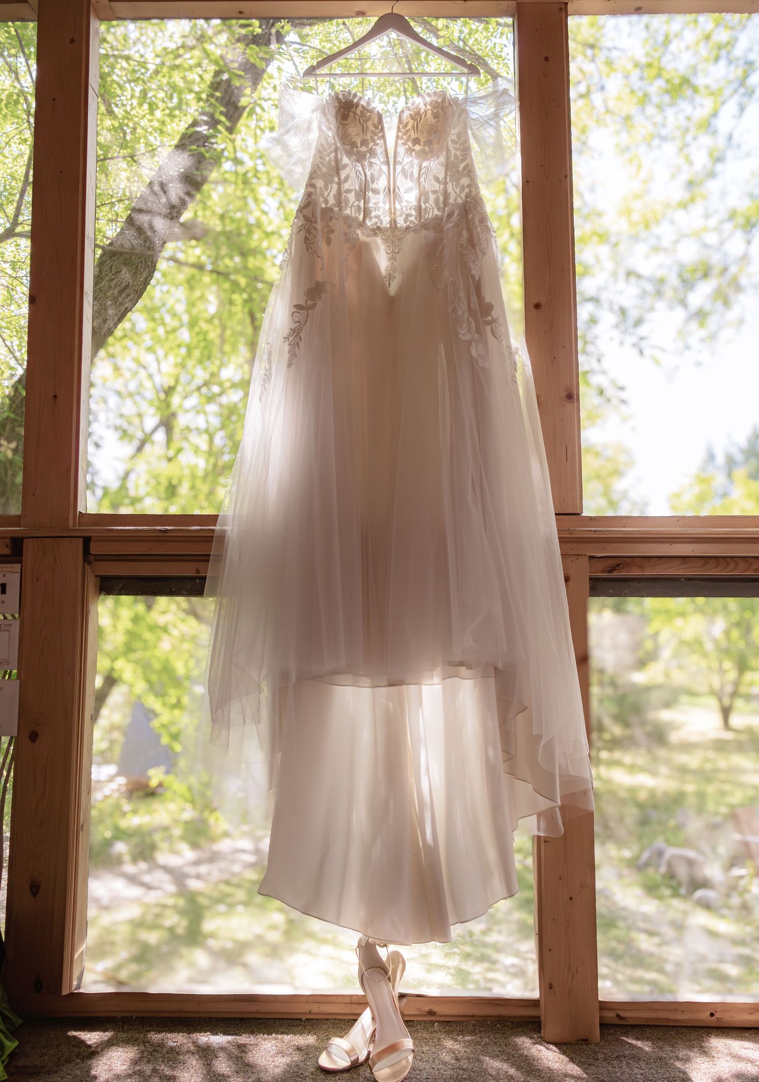 White wedding dresses hanging in sunlit windows creating an ethereal display of bridal gowns.
