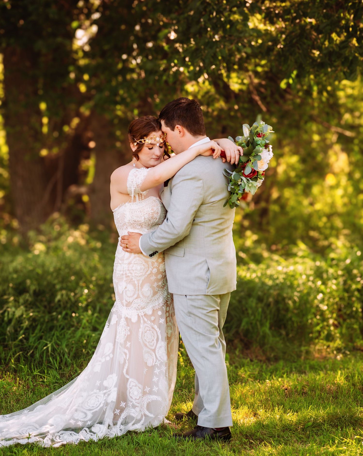 A couple shares an intimate moment in a sunlit garden setting during their wedding celebration.