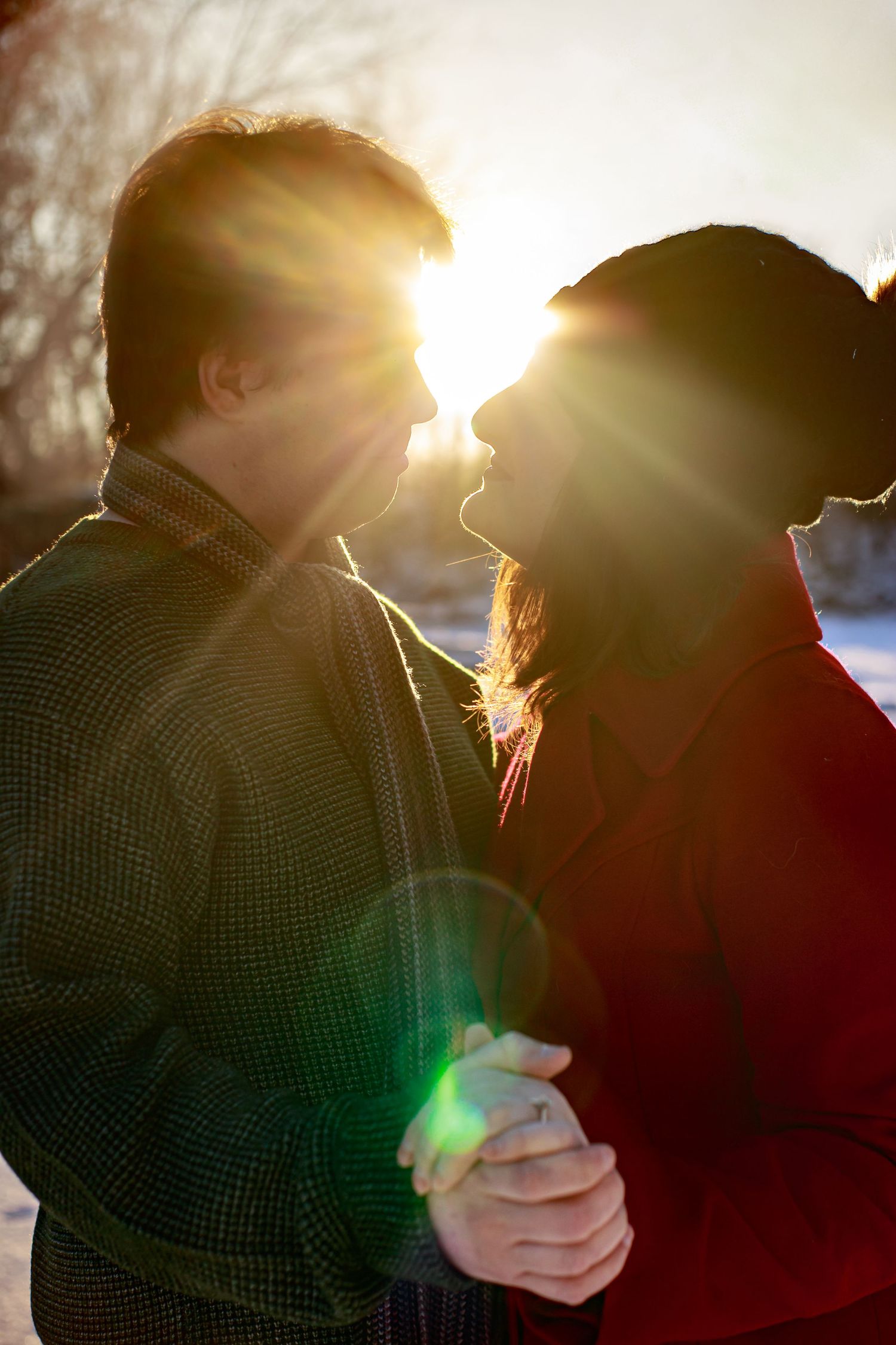 A romantic silhouette of a couple embracing in golden sunlight during sunset.