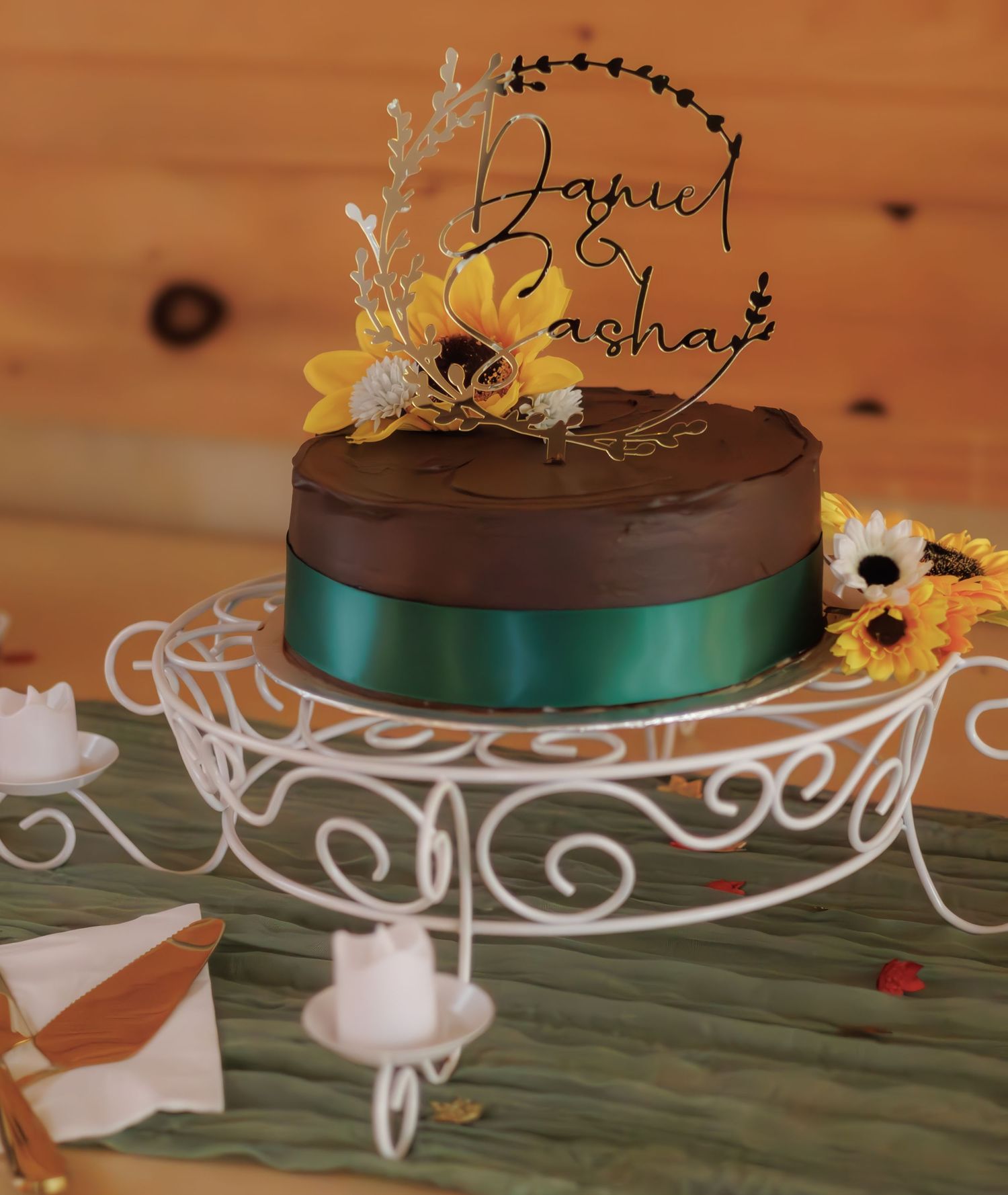 Chocolate wedding cake with decorative writing displayed on white ornate cake stands.