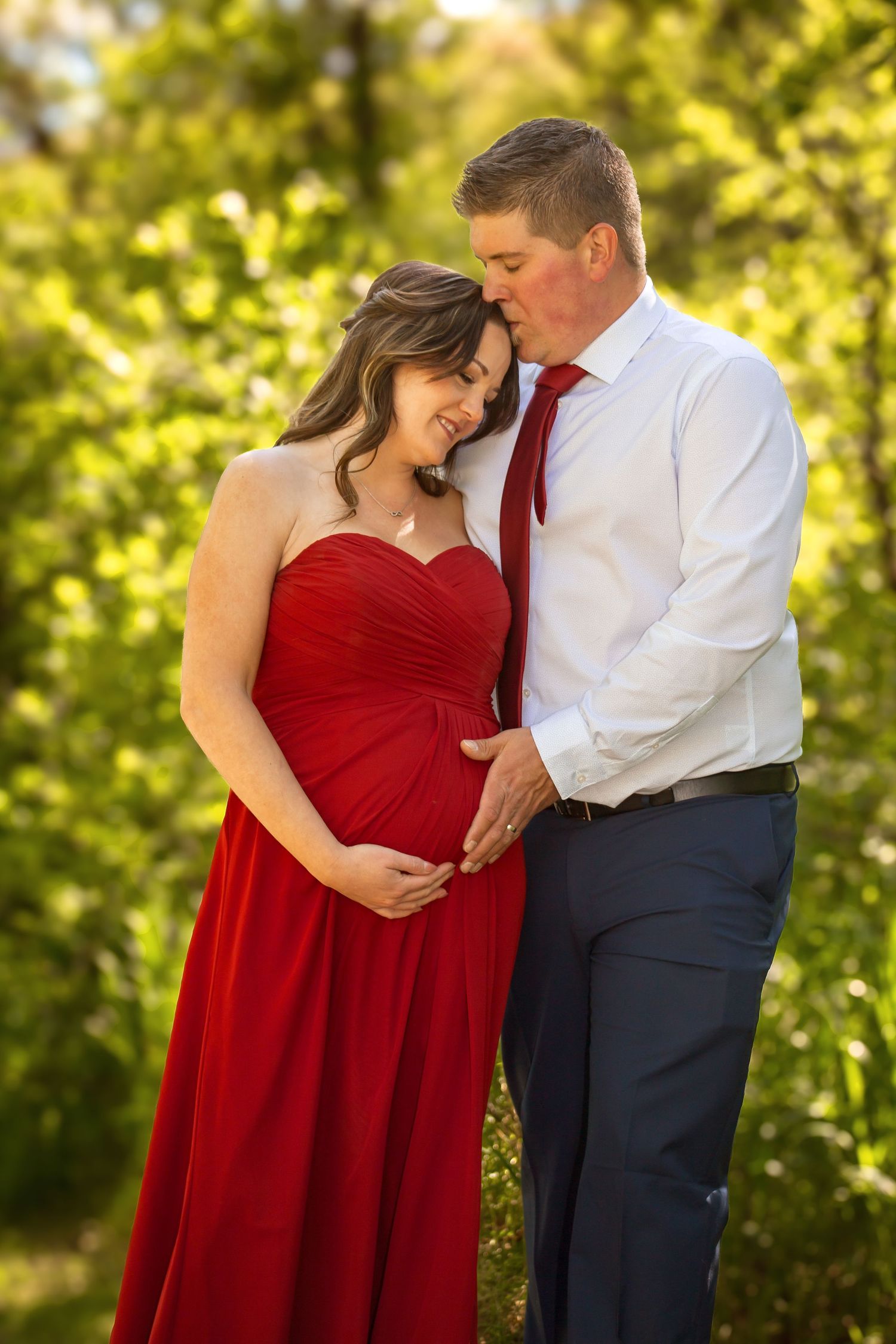 Romantic couple embraces outdoors with woman in flowing red dress.