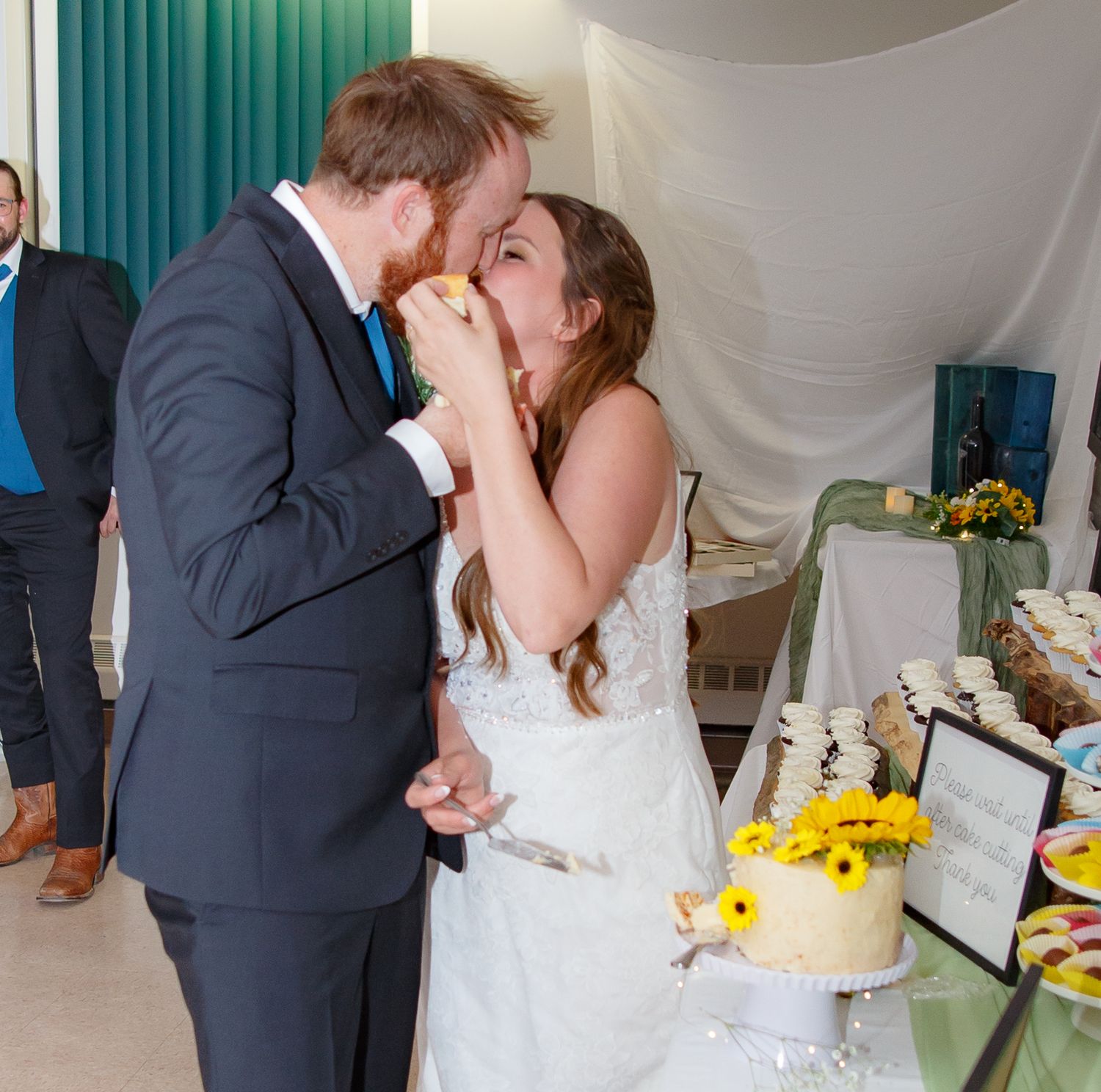 Wedding couple sharing intimate moment by dessert table decorated with sunflowers.