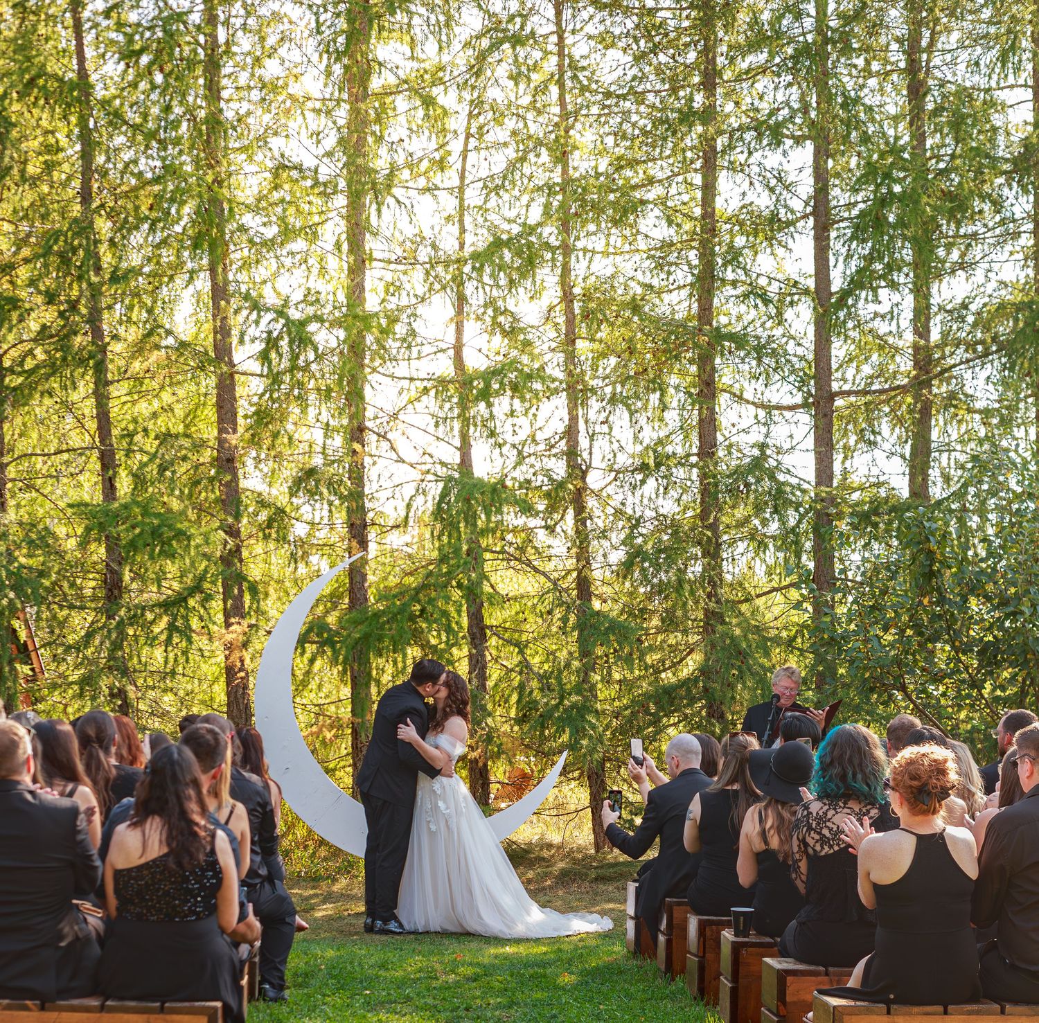 Outdoor wedding ceremony setup in a serene forest setting with natural sunlight filtering through trees.