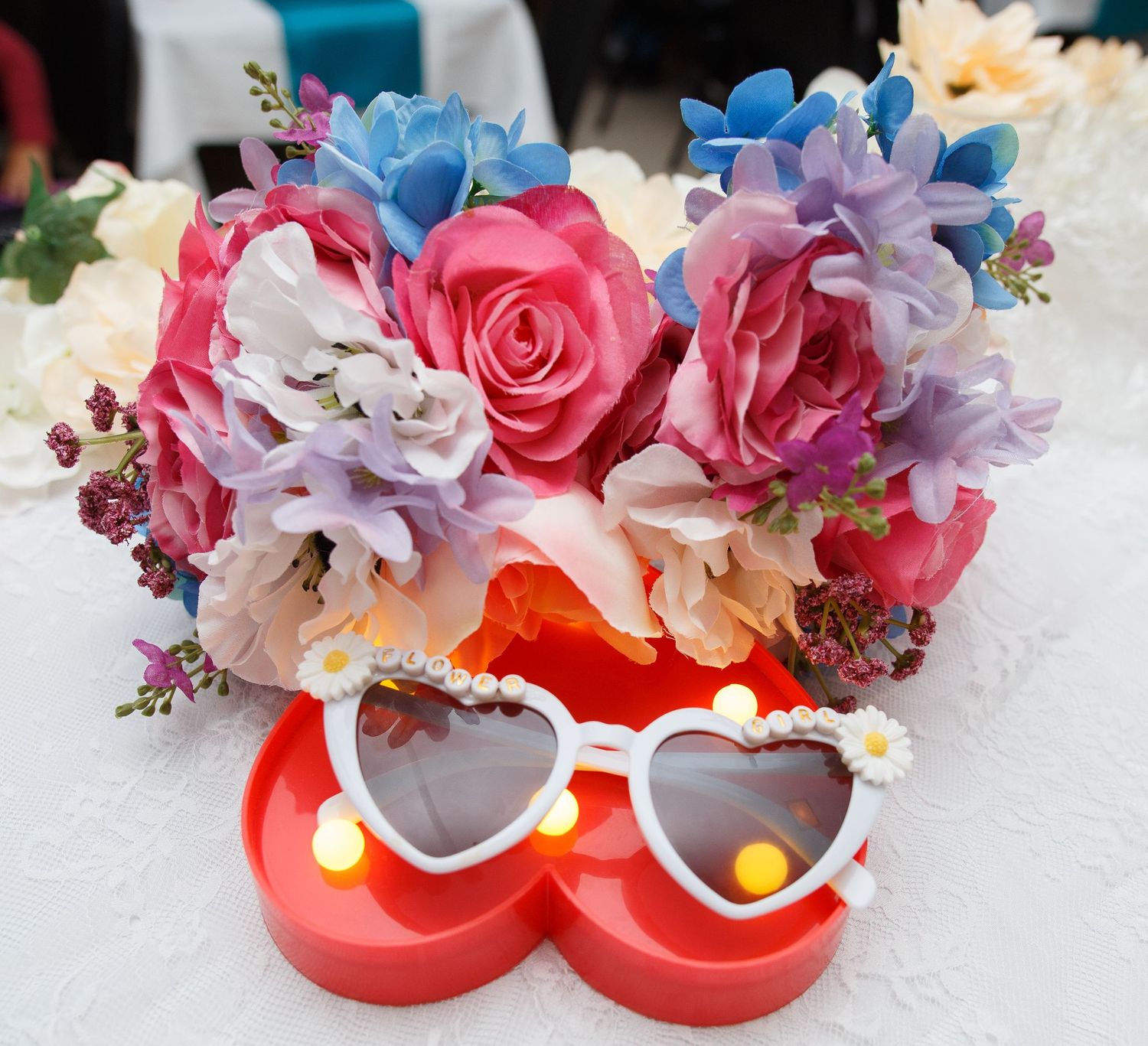 Red heart-shaped sunglasses decorated with colorful flowers and pearls for a romantic wedding accessory.