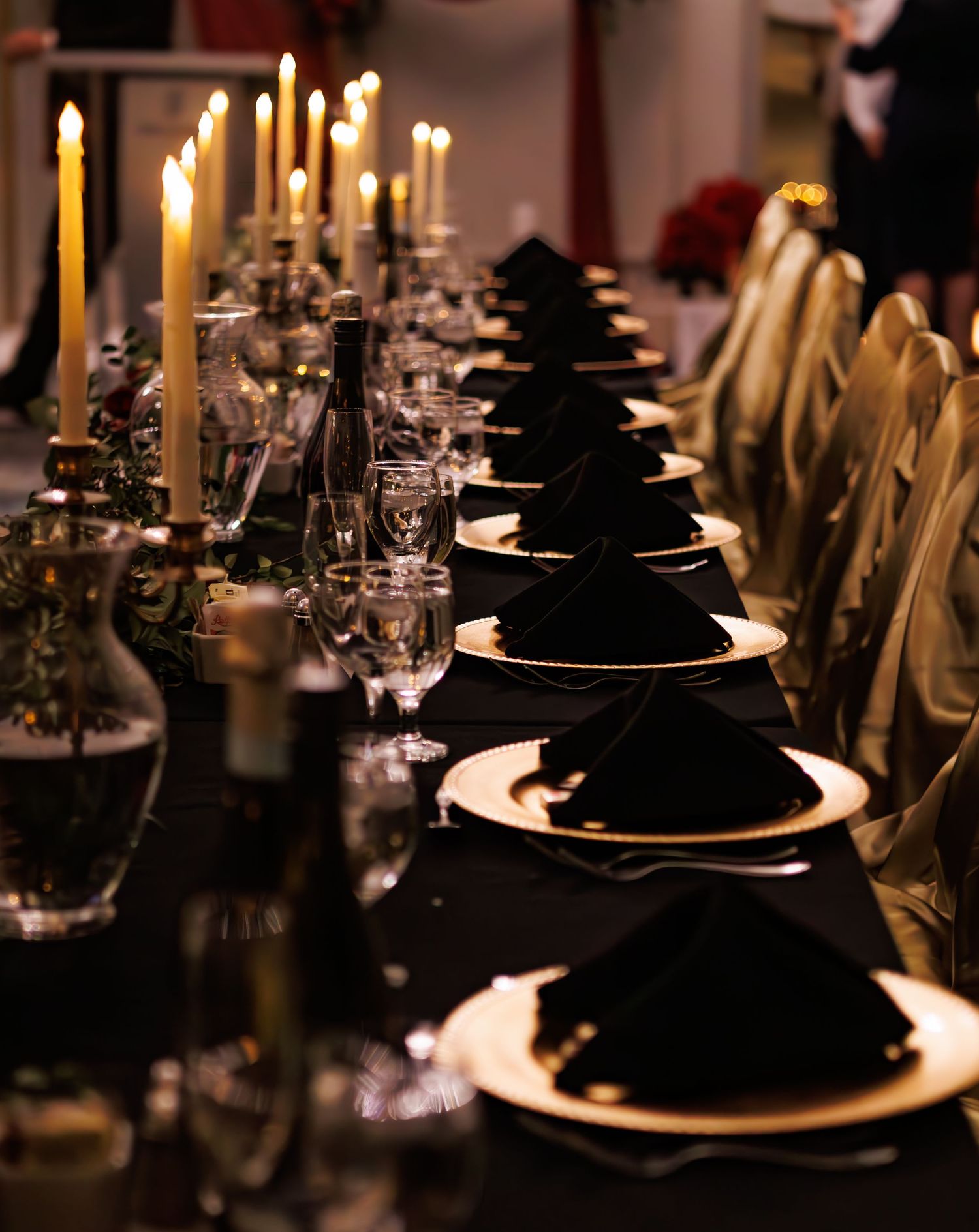 Elegant wedding reception table settings with black napkins and glowing candles create a dramatic ambiance.
