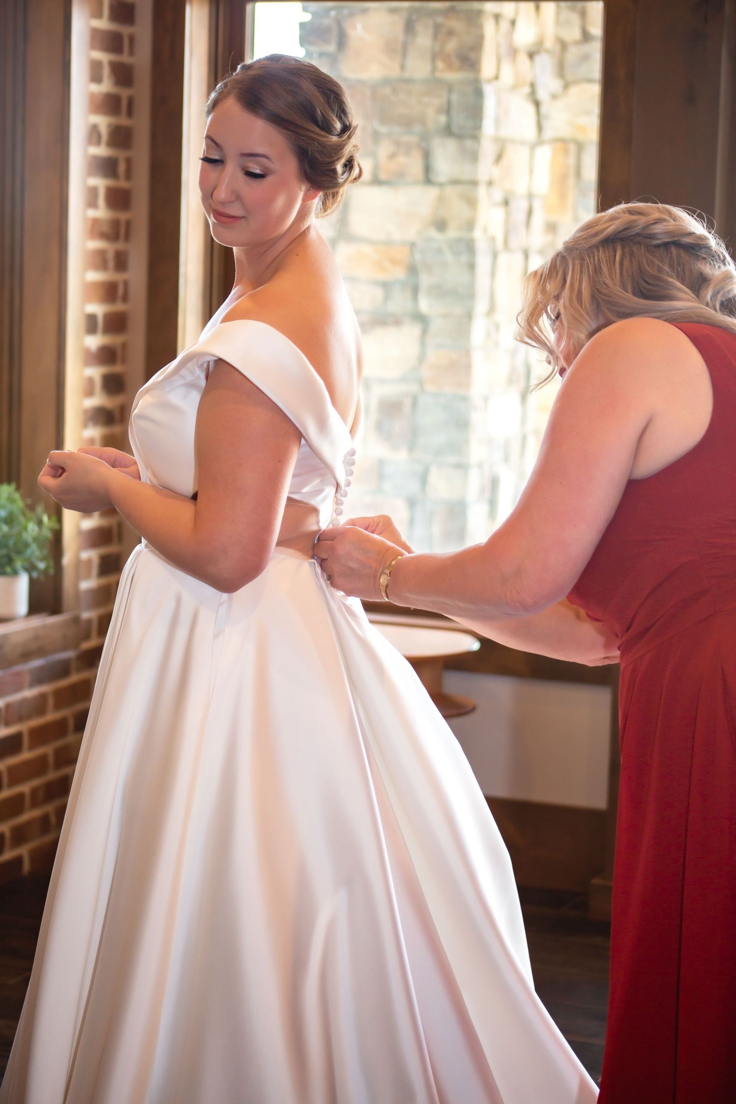 Bride in elegant white gown getting final dress adjustments before the ceremony.