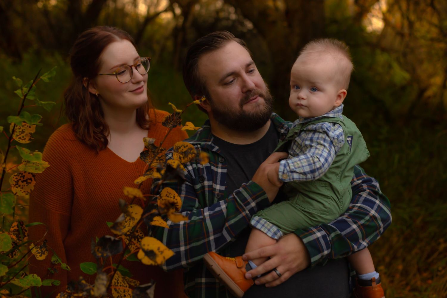 A cozy family portrait surrounded by fall foliage and sunflowers.