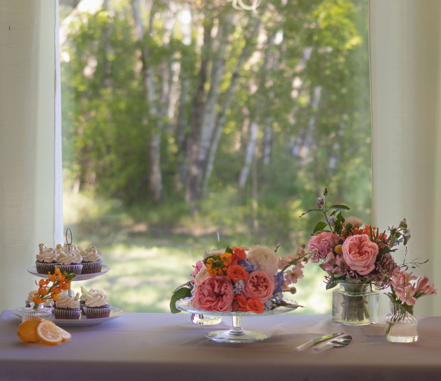 Table decorated with pink and coral flowers in rustic outdoor setting.