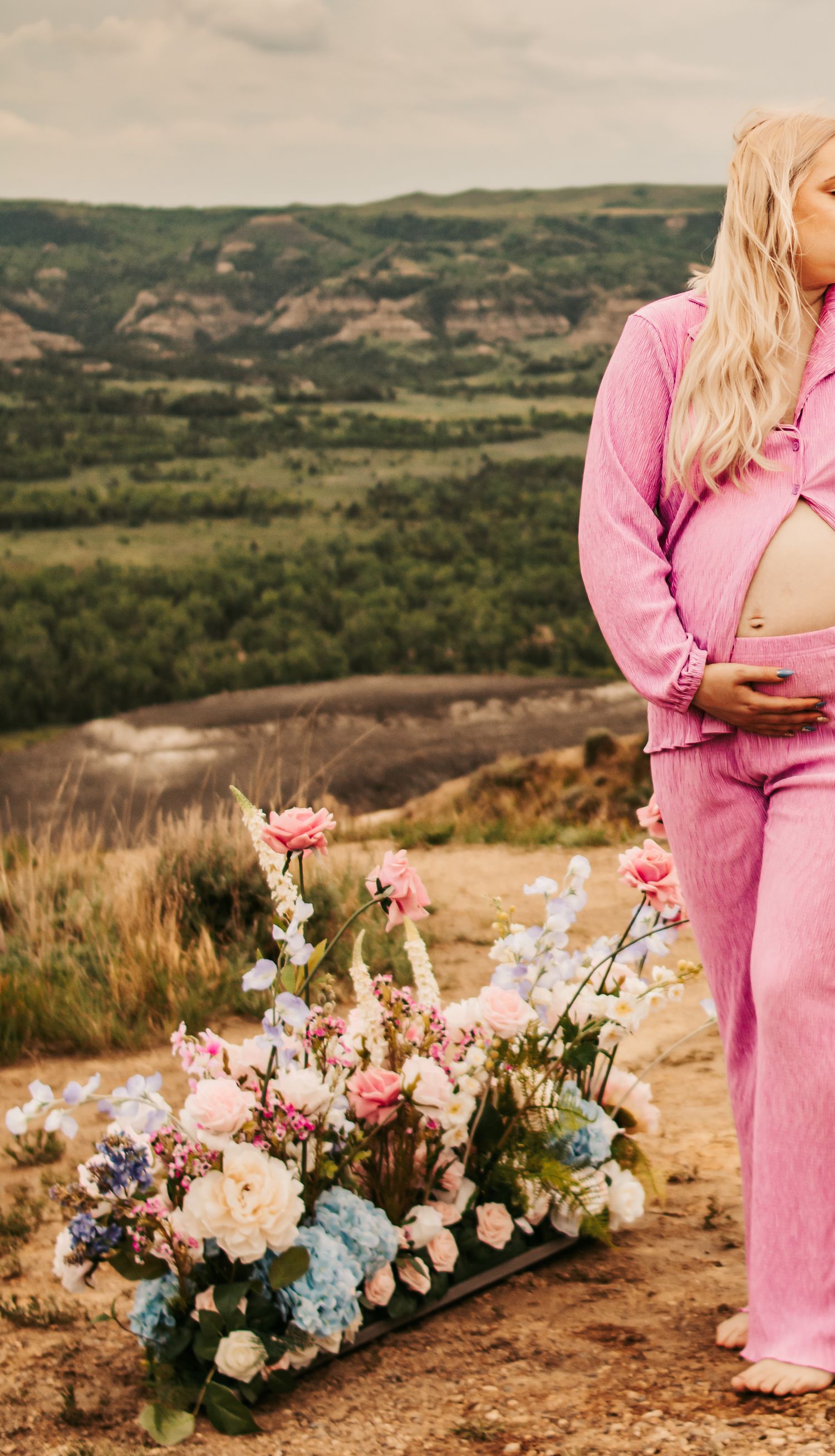 Beautiful floral arrangement with pink and blue flowers against a scenic mountain landscape backdrop.