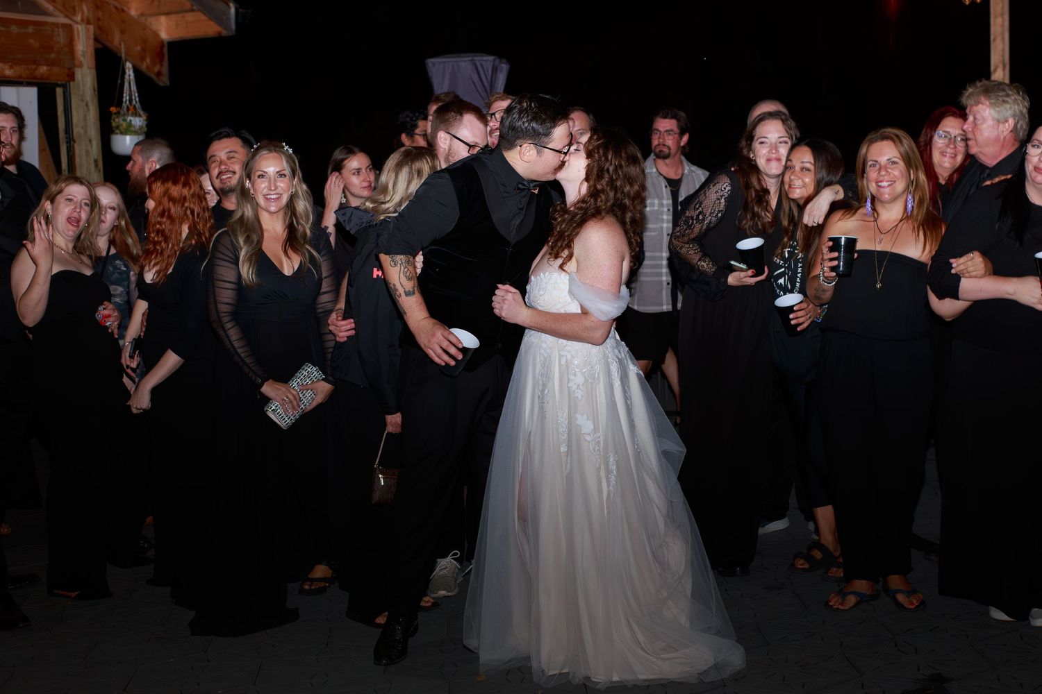 Wedding guests watching the couple's first dance at an evening reception.