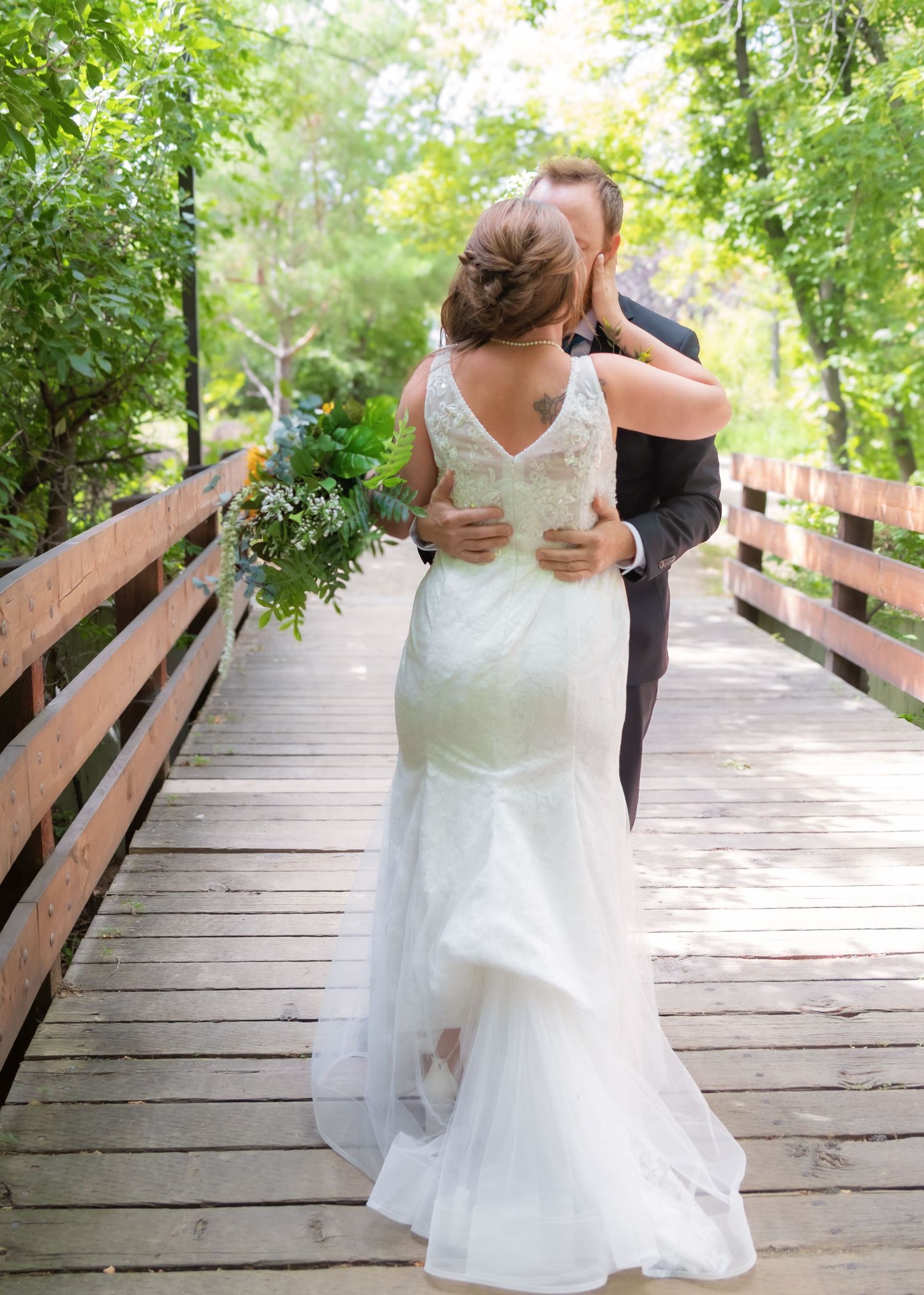 Romantic wedding photos on a wooden bridge surrounded by green foliage.