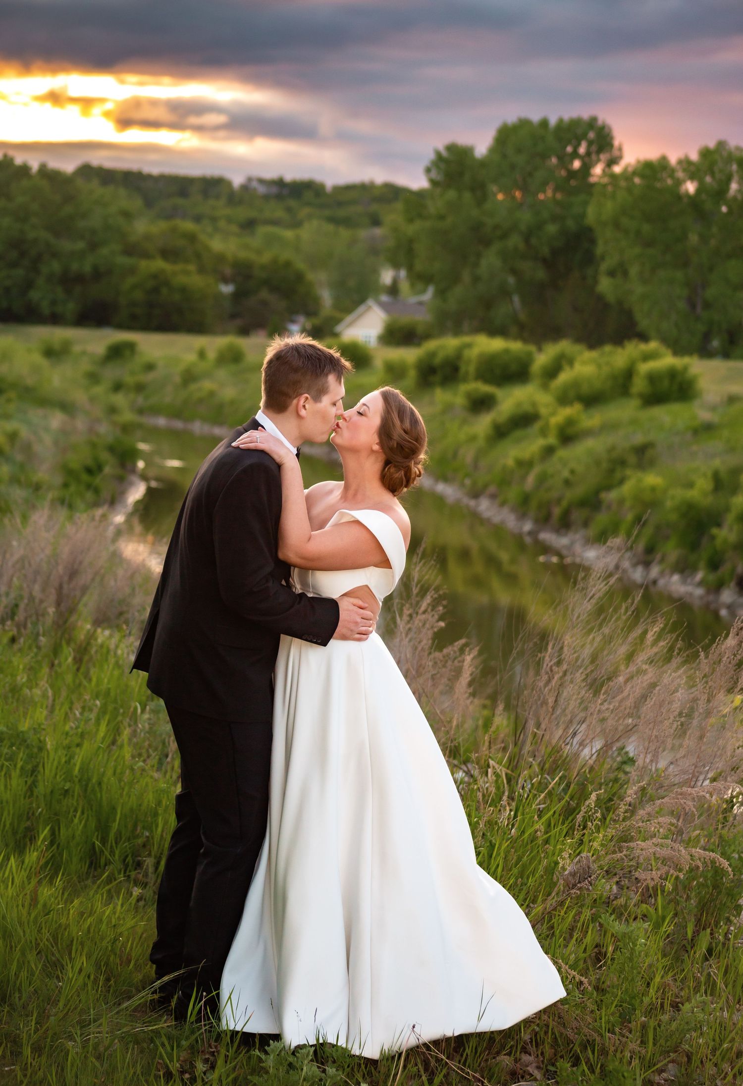 Romantic sunset wedding portrait in a field of tall grass and rolling hills.