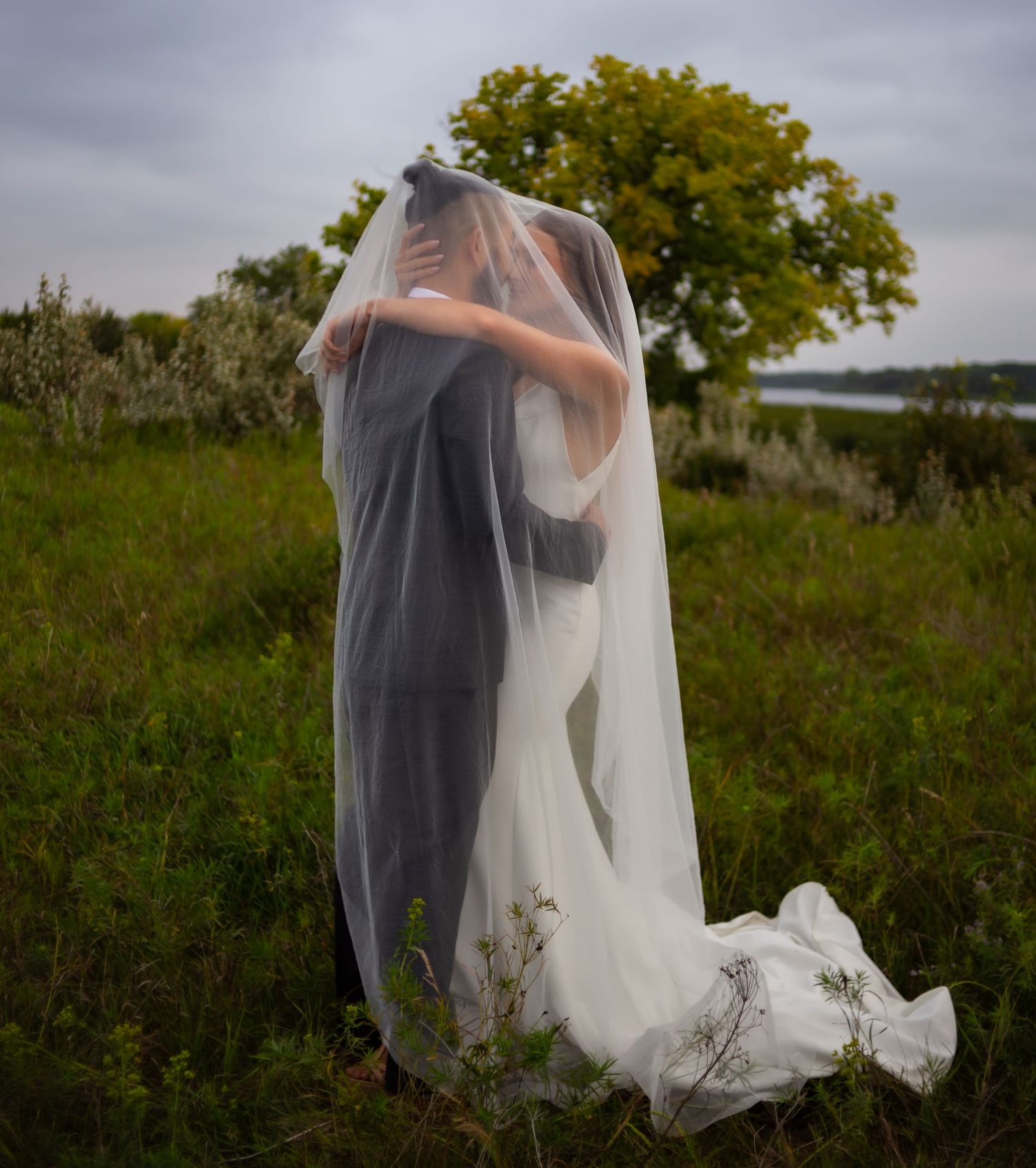 An intimate wedding moment captured in a natural setting with flowing veil details.