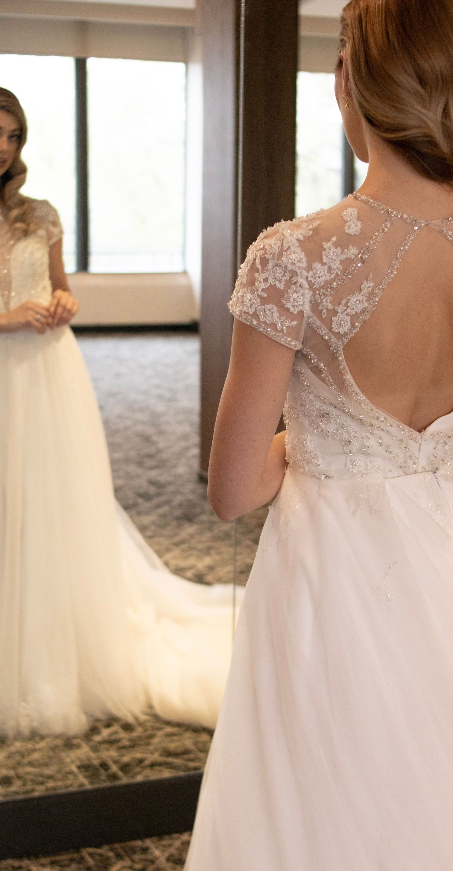 Close-up details of intricate lace and beading on back of white wedding dress.