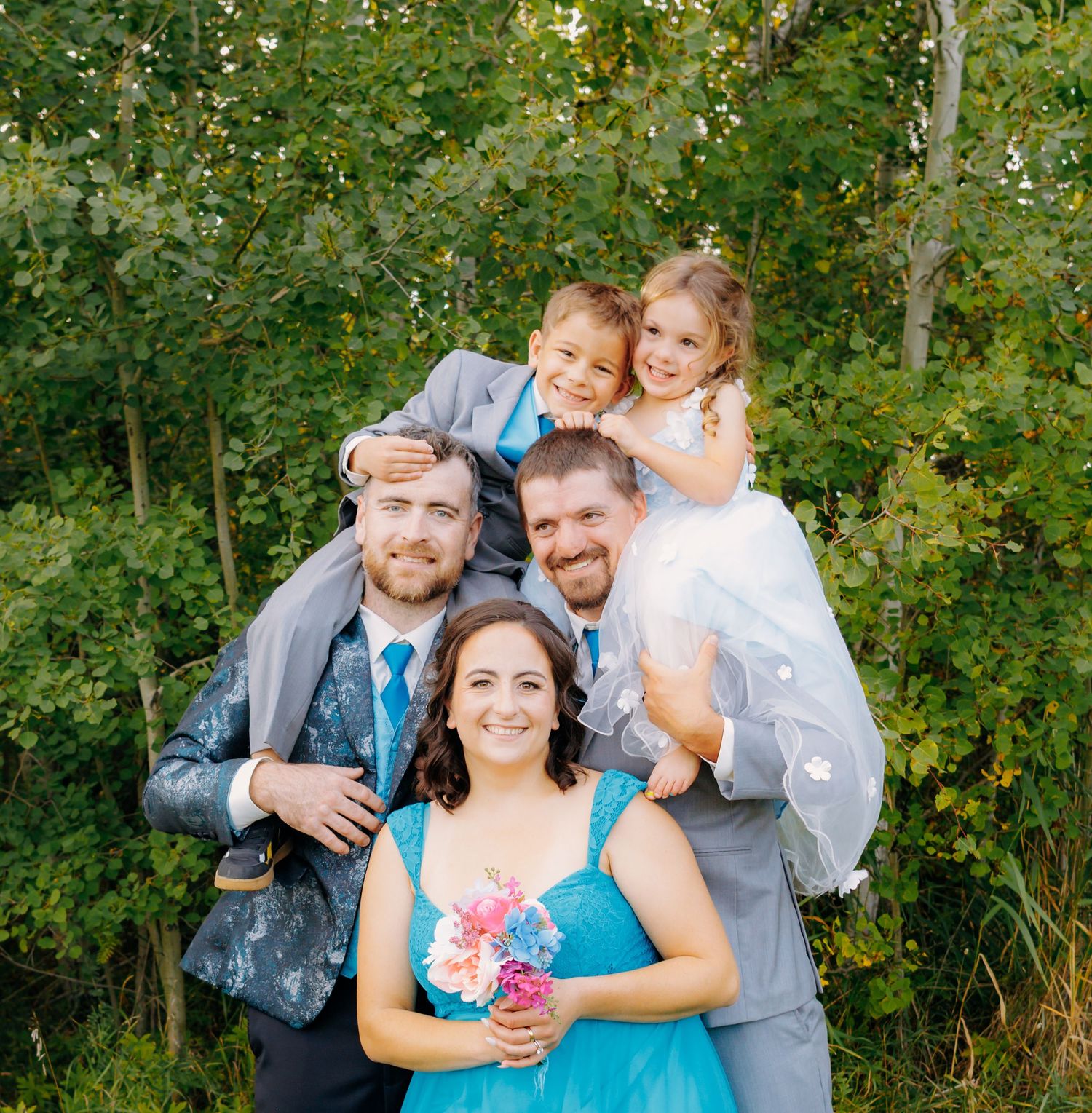 Candid wedding party moments captured in natural outdoor setting with greenery.