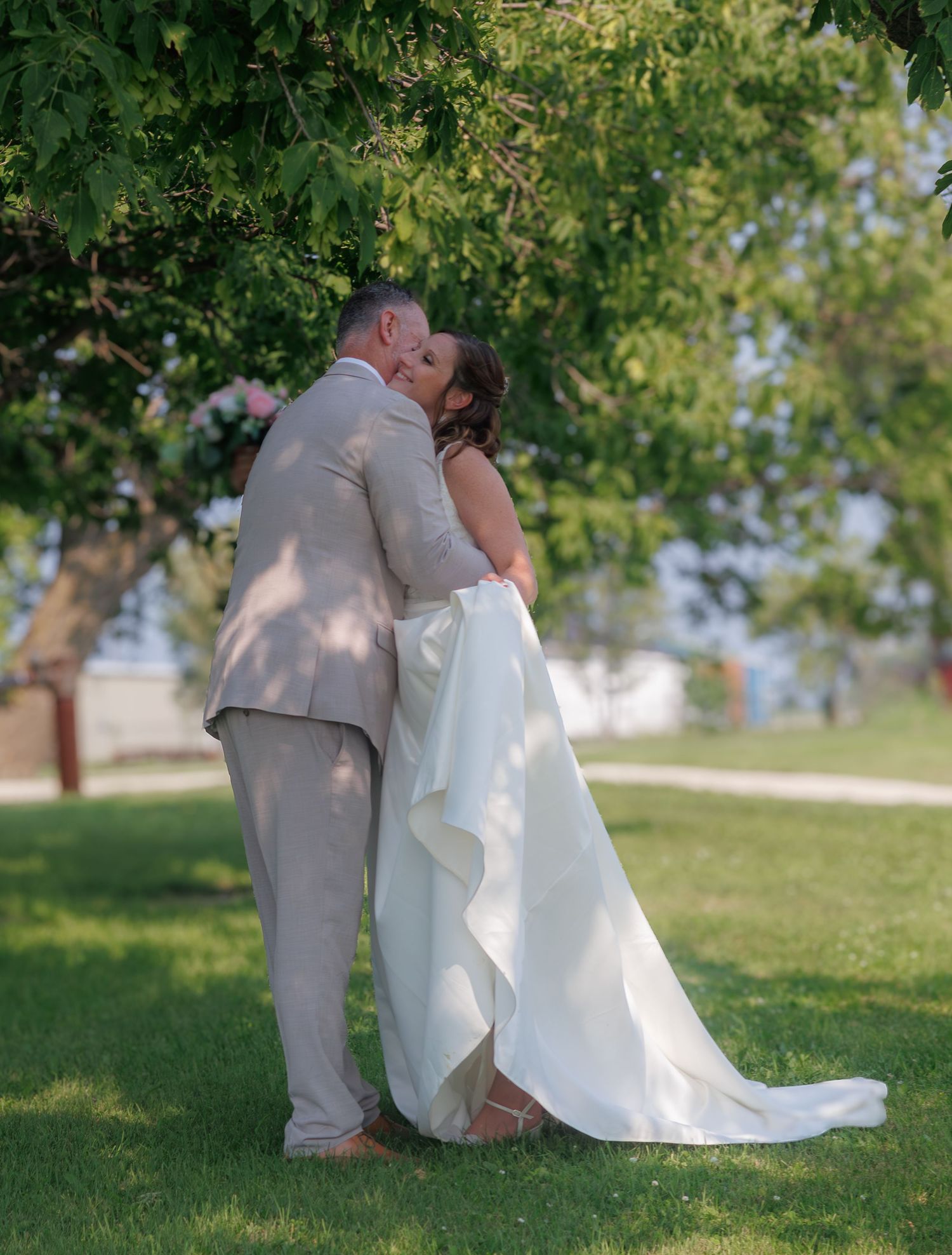 Intimate wedding moment captured in a sun-dappled garden setting.