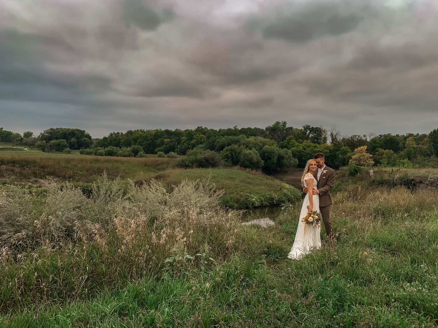 Rolling hills and meadows create a romantic backdrop for a wedding photoshoot at sunset.