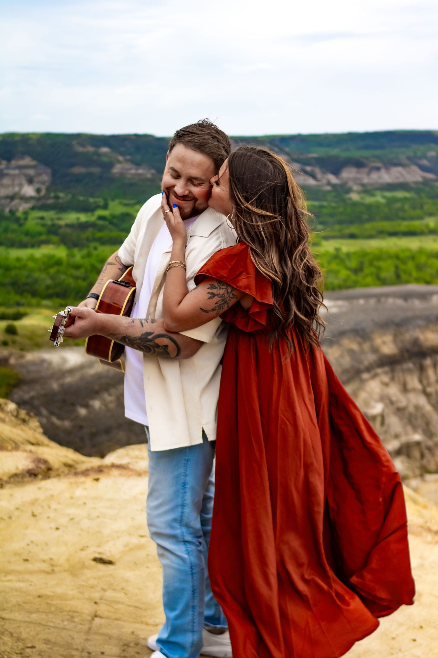 Romantic outdoor moment with guitar on scenic mountain overlook.
