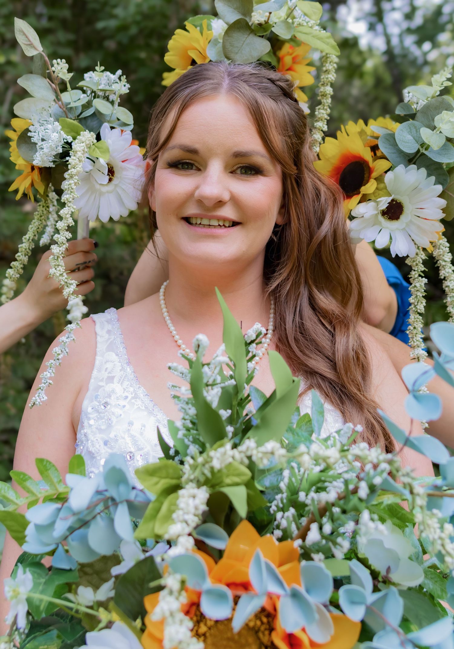 Vibrant wedding bouquet featuring sunflowers, white daisies, and eucalyptus leaves against a natural outdoor backdrop.