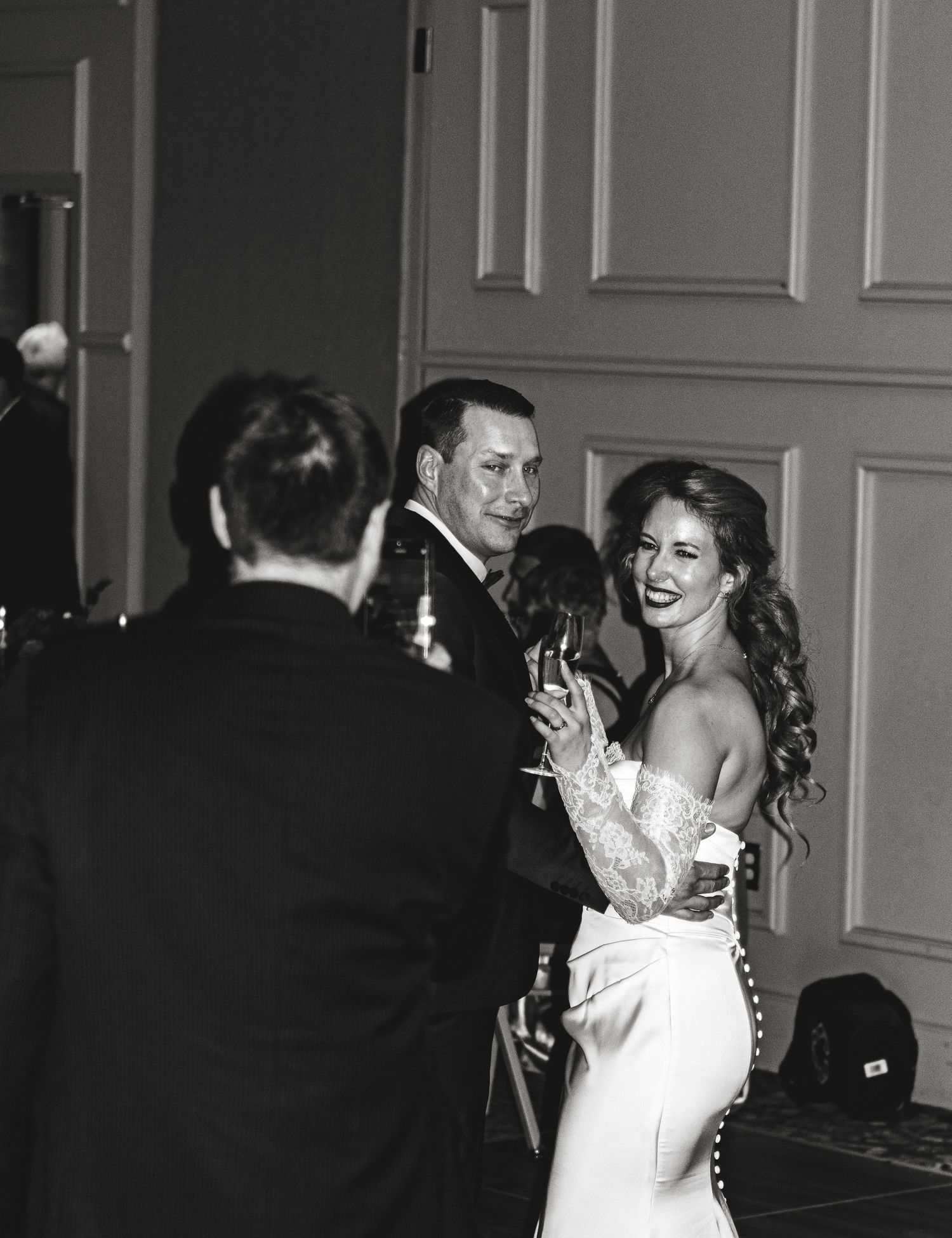 A joyful celebration moment captured in black and white at an elegant indoor reception.