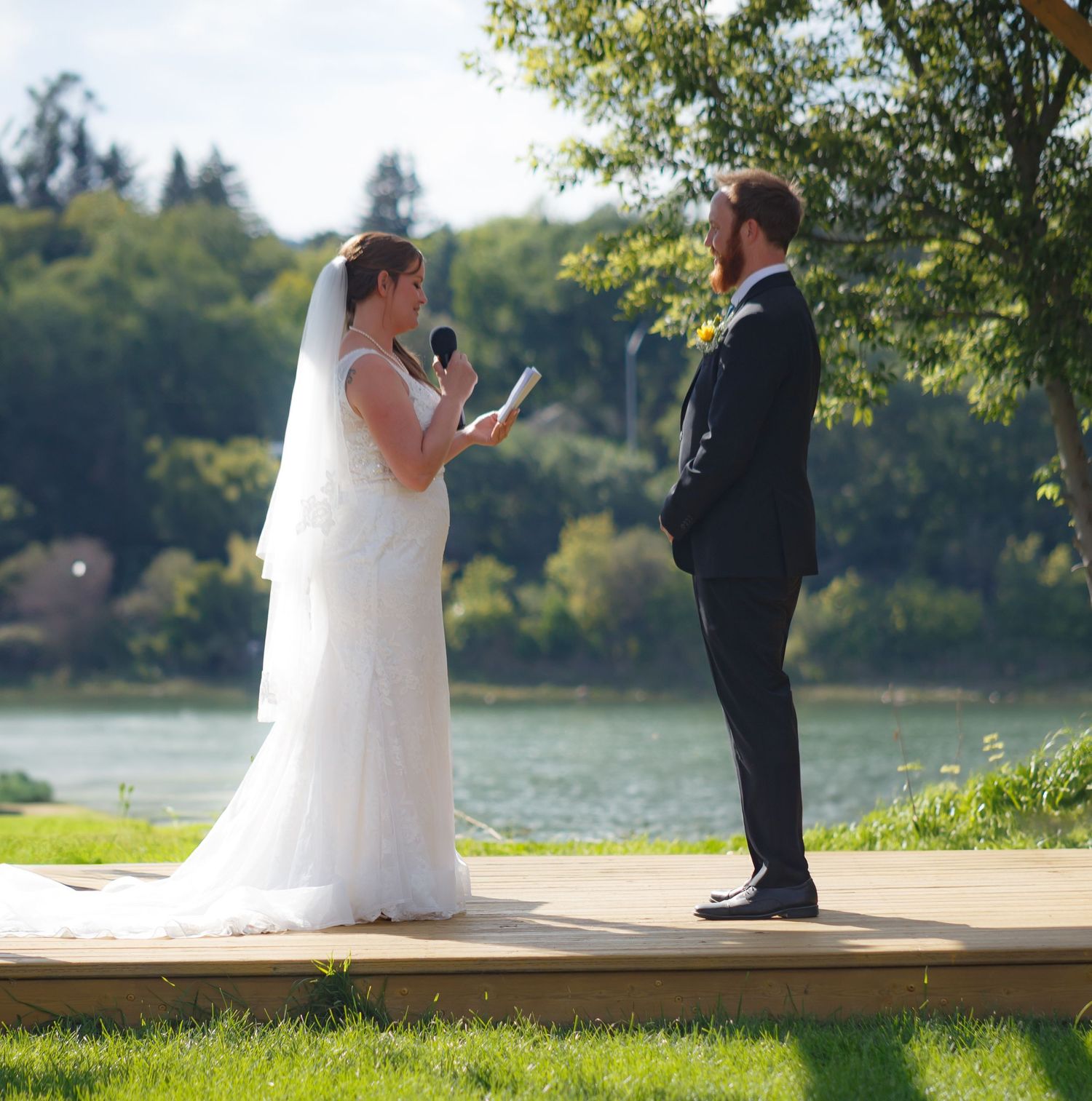 Couple exchanging vows during outdoor lakeside wedding ceremony.