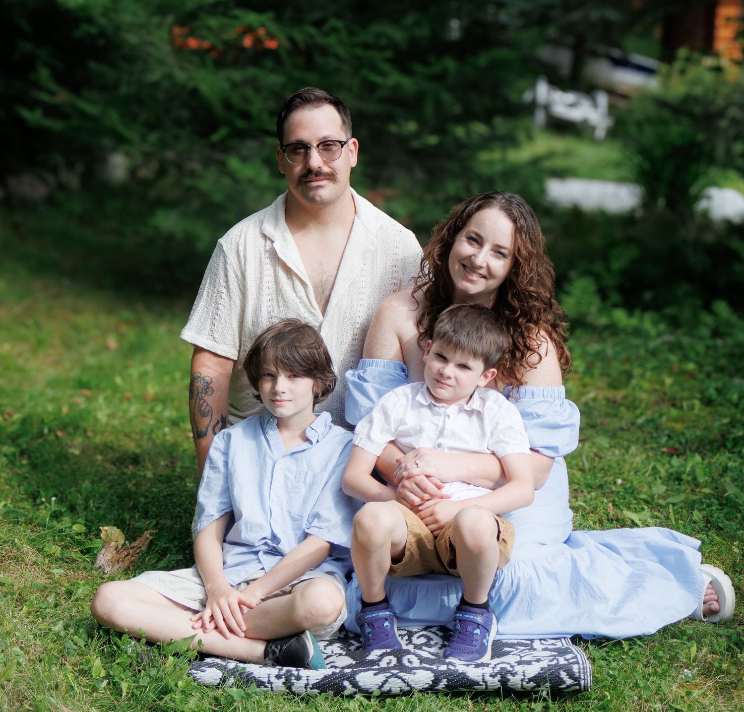 Family relaxes together on grass during outdoor photo session.