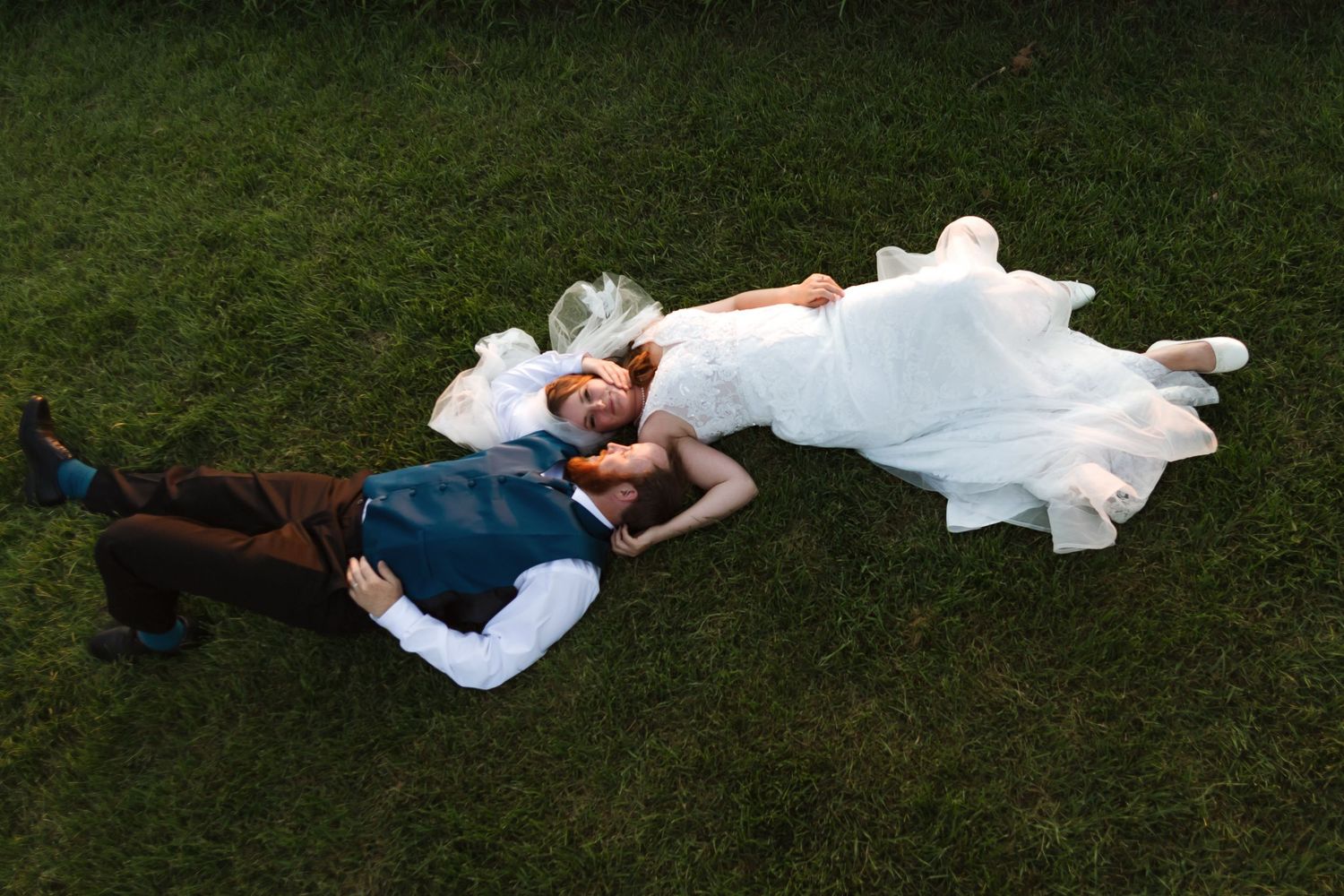 Couple lying in grass during sunset wedding photo session.