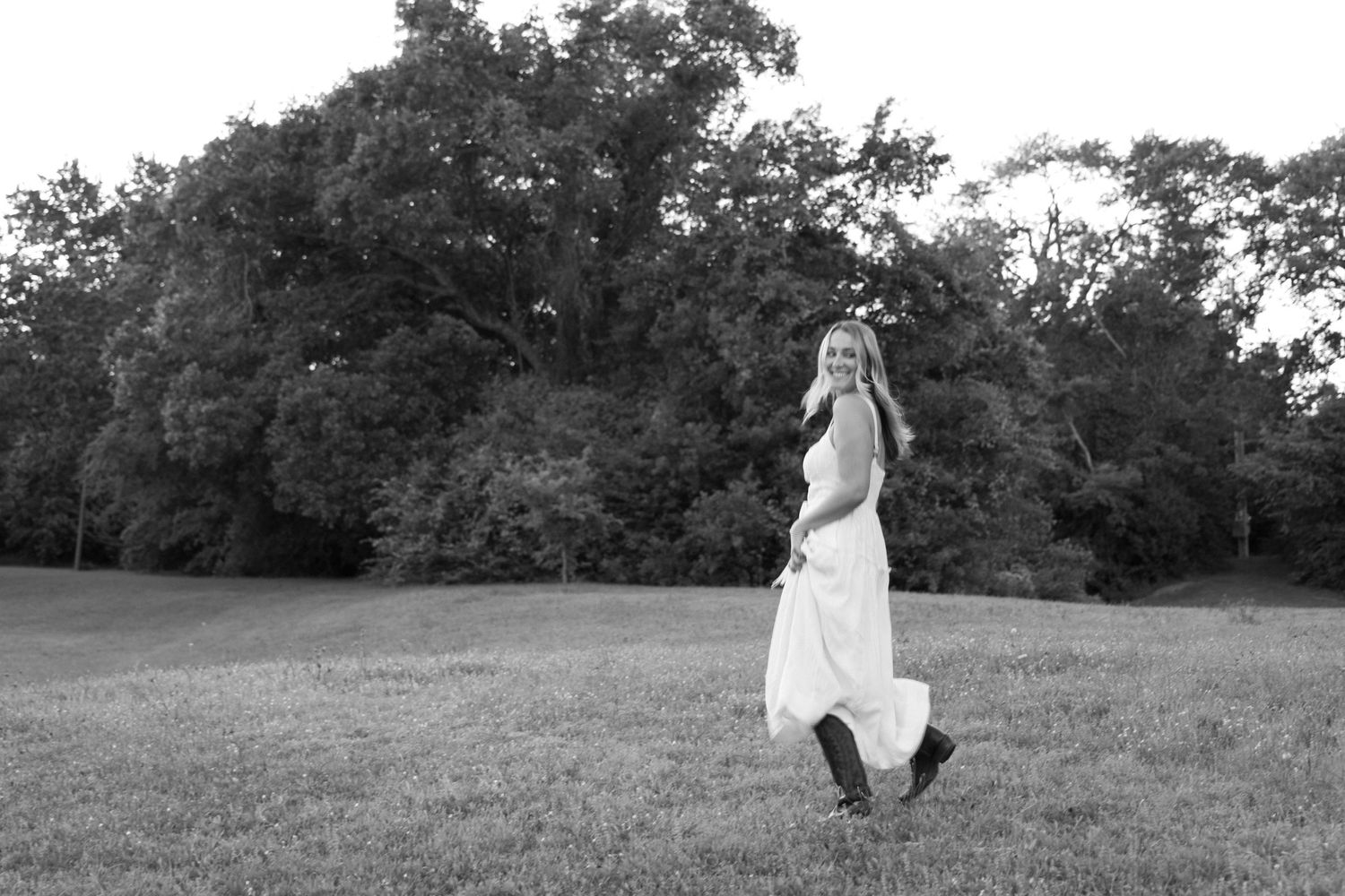 Black and white portrait series in a grassy field showing movement and dance-like poses against nature.