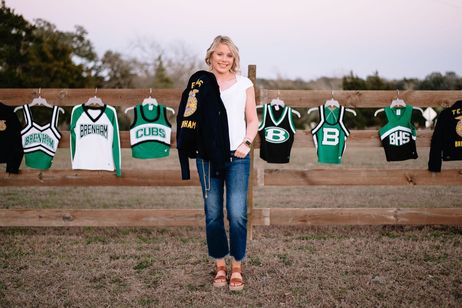 Row of green and white sports jerseys displayed on wooden fence.