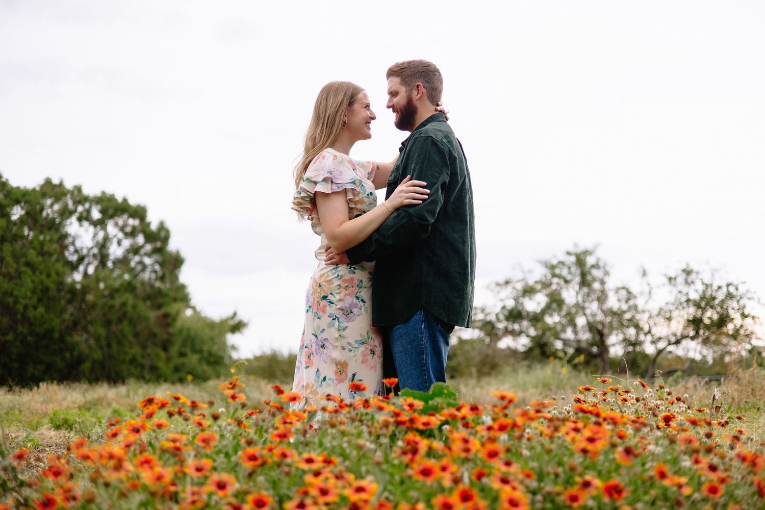 A couple stands together in a vibrant field of red poppies during a romantic outdoor photo session.