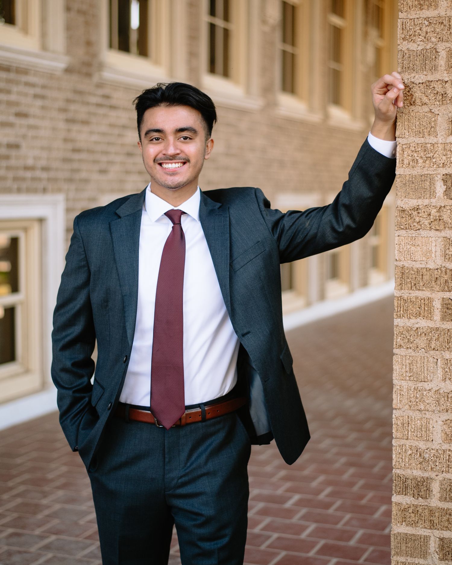 Professional in dark suit and red tie posing with expressive gestures.