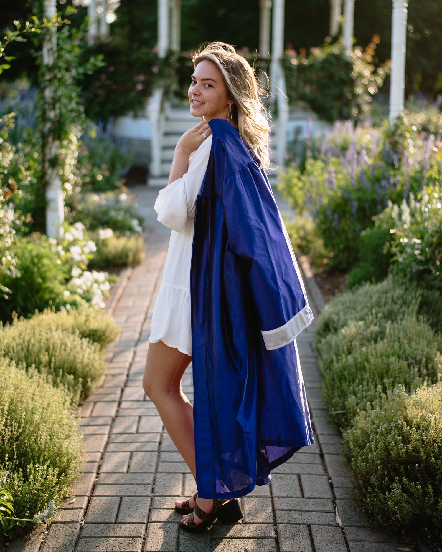 Garden pathway scene with figure in flowing blue cape and white dress.