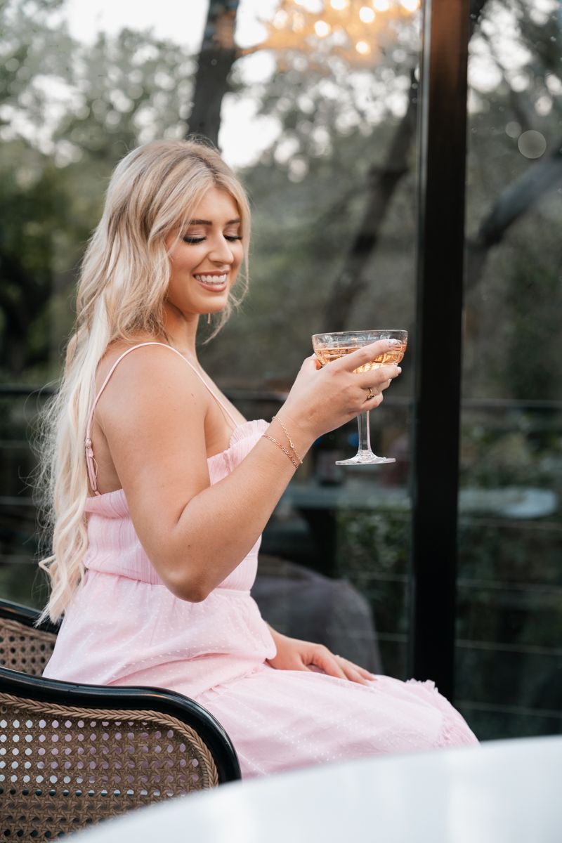 Relaxed outdoor scene with pink dress and cocktail on patio chair.