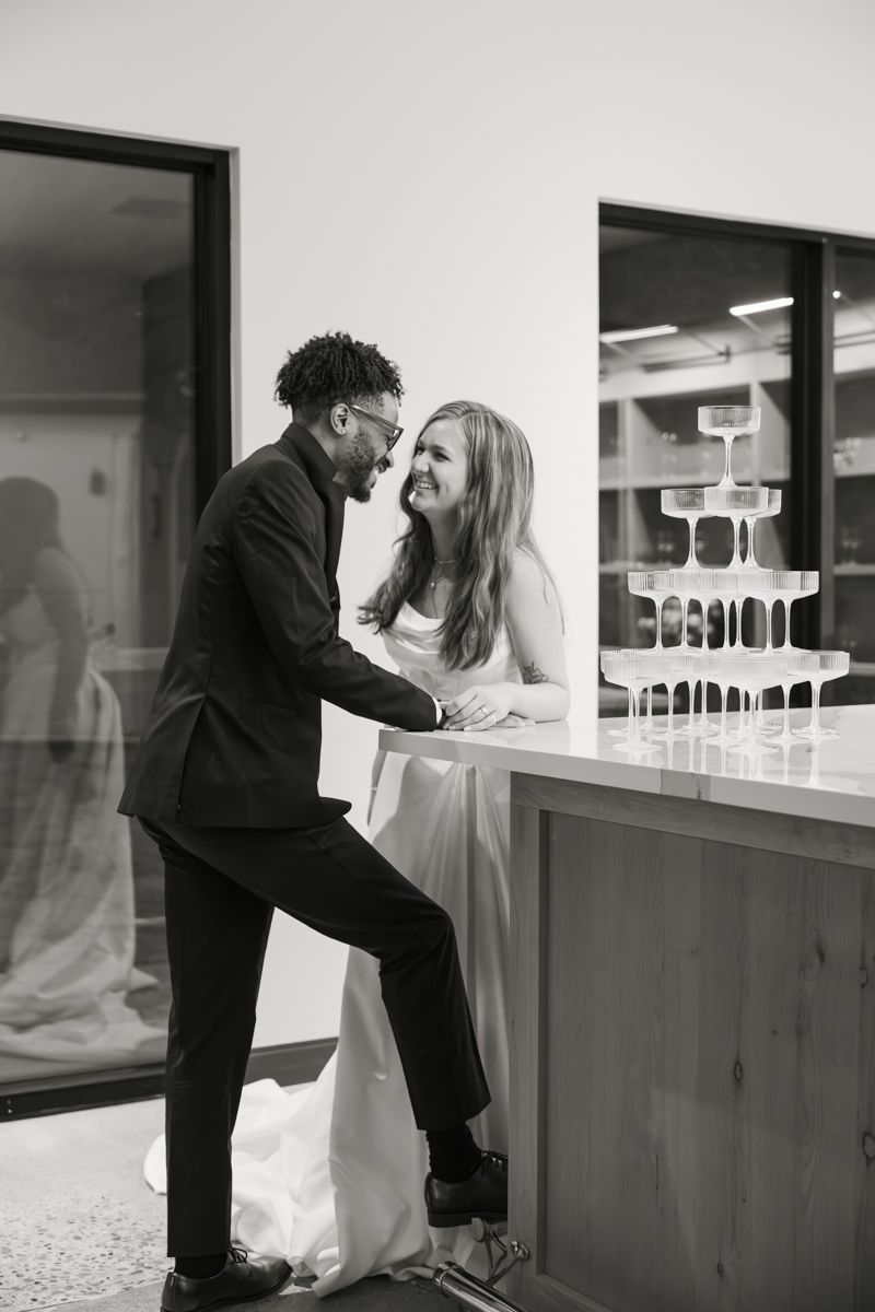 A candid black and white wedding moment captured at a modern bar counter.