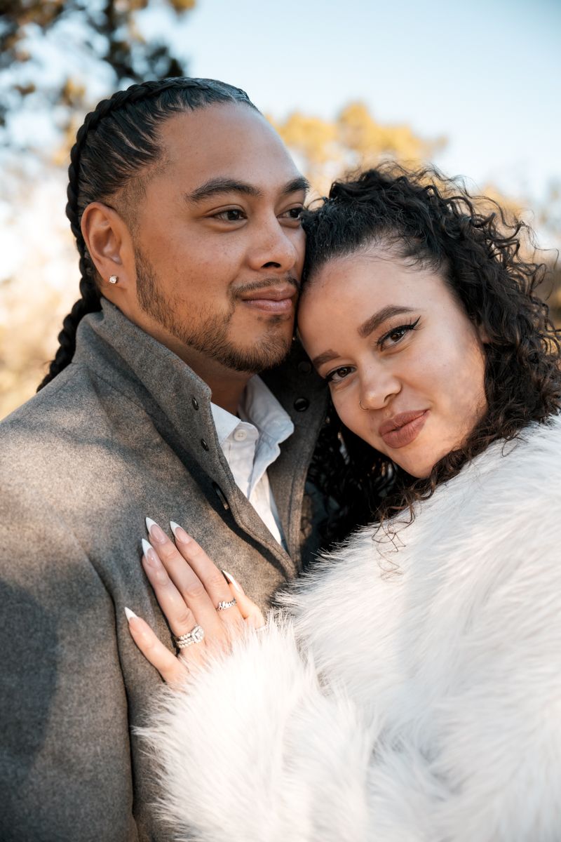 Intimate outdoor portrait of a couple in winter attire against natural backdrop.
