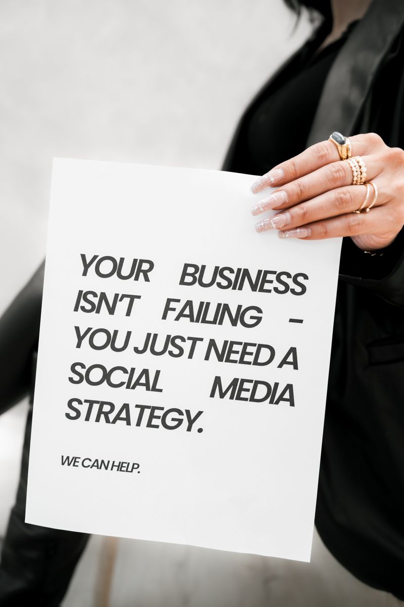 Close up of hands holding social media strategy sign with minimal black text on white paper.
