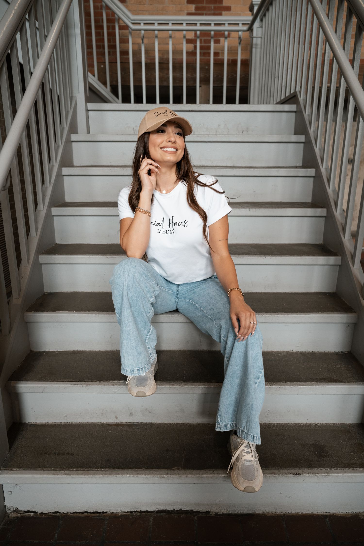 Casual lifestyle photo showing person sitting on concrete stairs wearing jeans and white t-shirt.