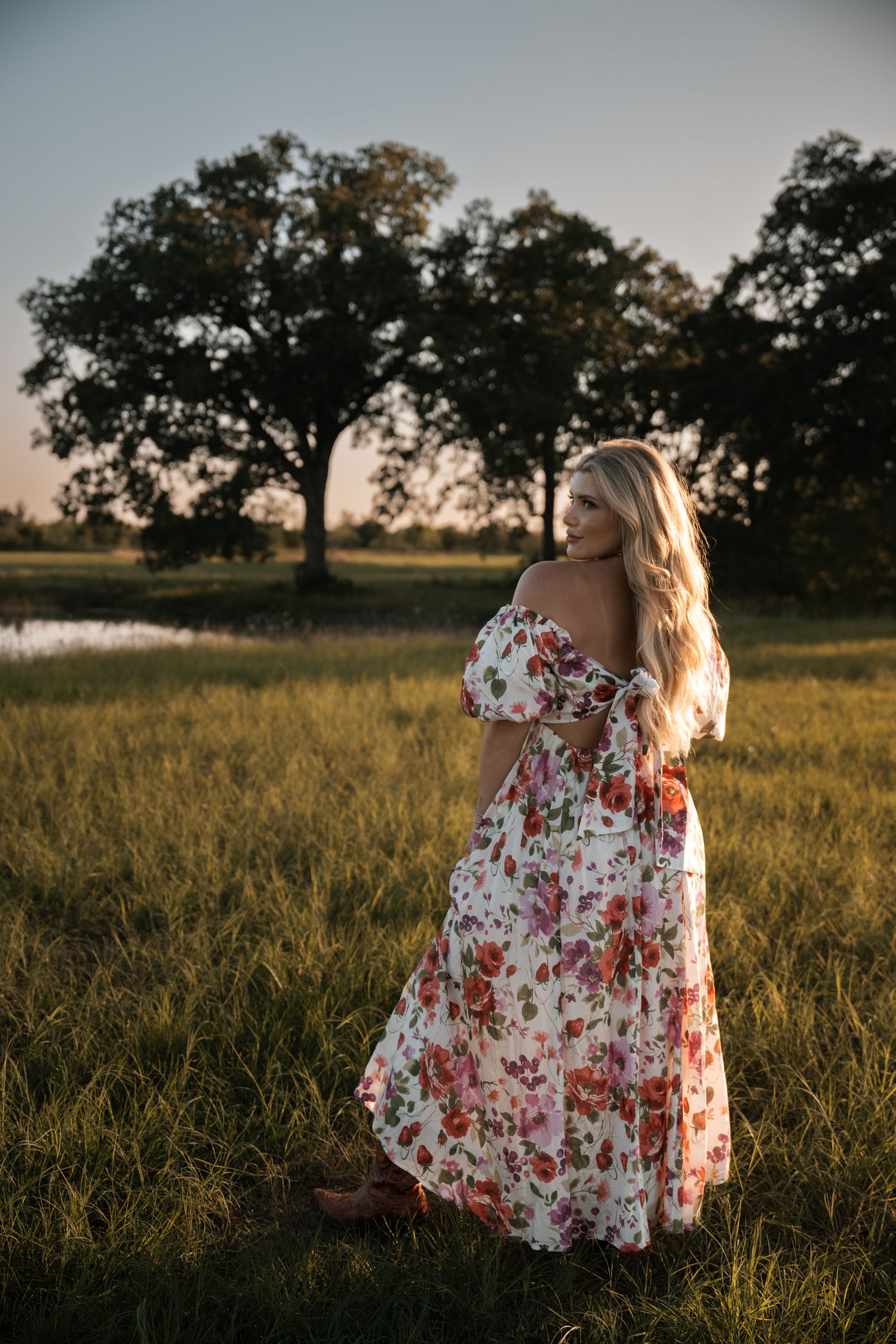 Romantic floral maxi dress captured at sunset in rural field setting.
