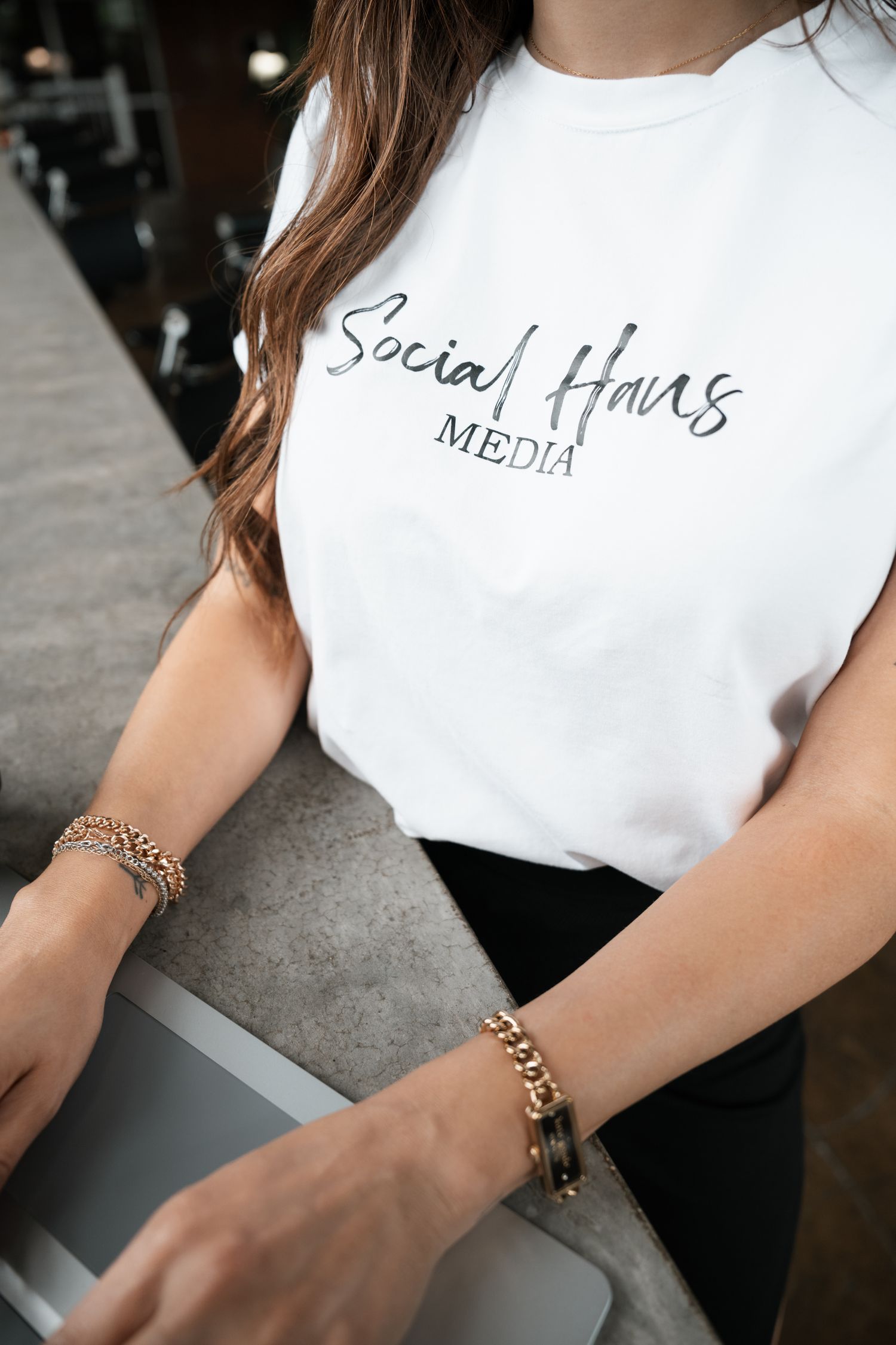 Close-up of white Social Haus Media t-shirt with gold chain accessories.
