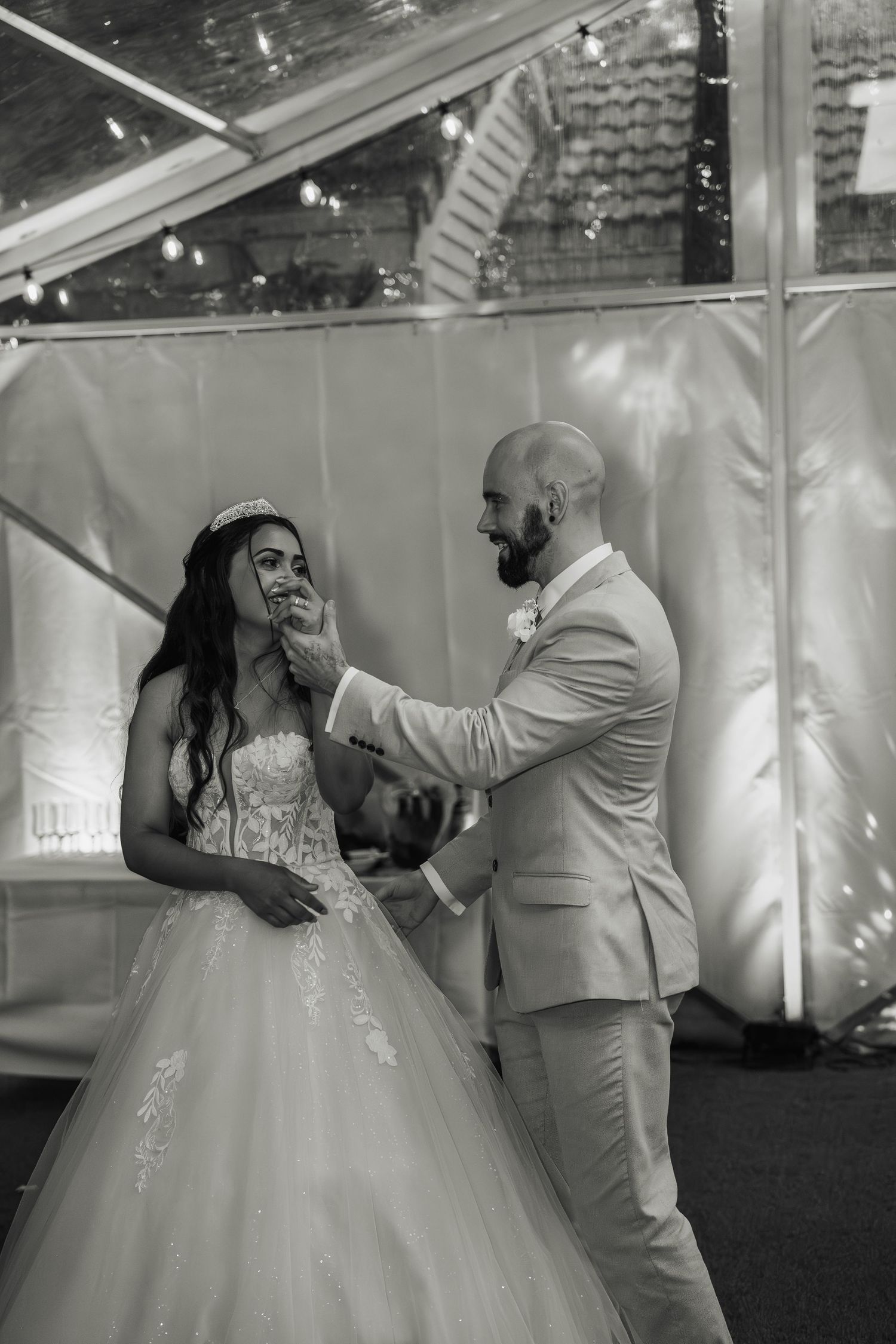Black and white photo of groom tenderly touching brides face during wedding reception dance.