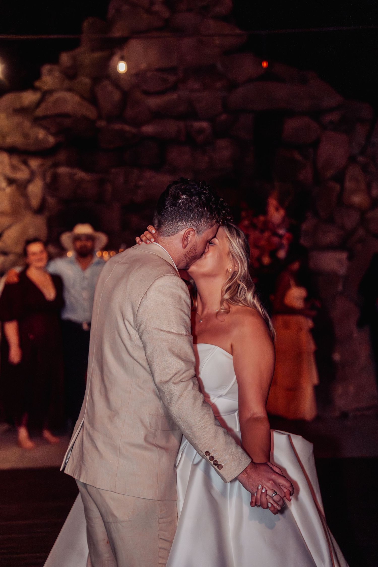 Bride and groom share a passionate kiss during their first dance at evening wedding reception.