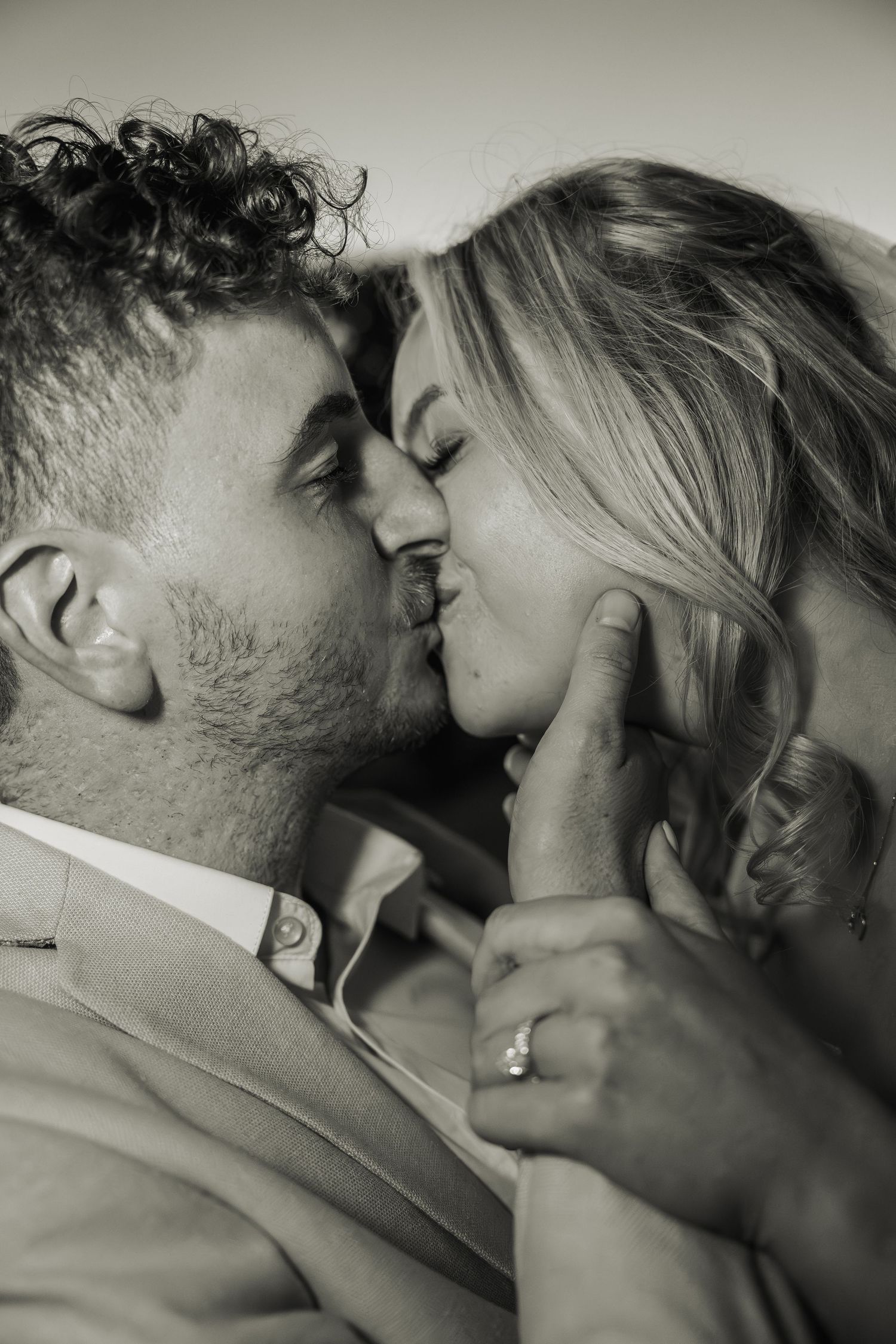 Black and white close-up of bride and groom sharing a romantic kiss on their wedding day.