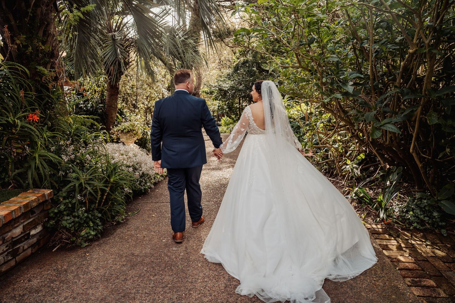 Couple strolling through a scenic garden path surrounded by tropical foliage.