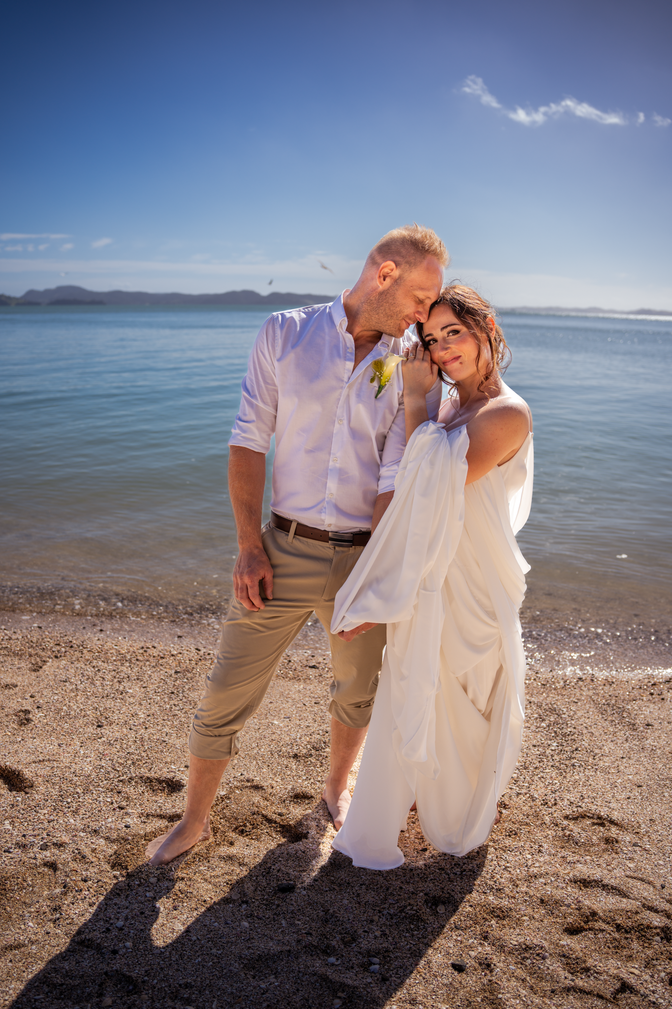 A romantic beach wedding scene with a couple sharing an intimate moment by the ocean.