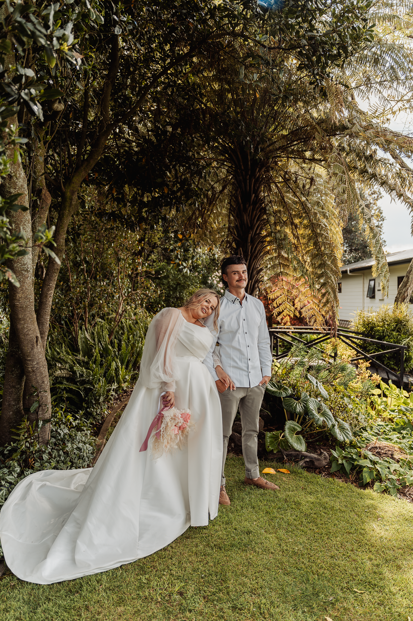 Garden wedding portrait with flowing white gown and natural landscape setting.