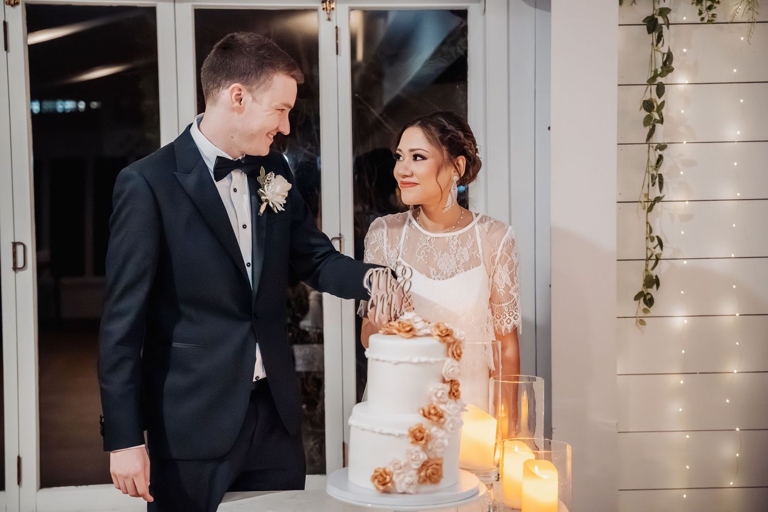 Candlelit wedding venue with elegant white trim and hanging greenery decorations.