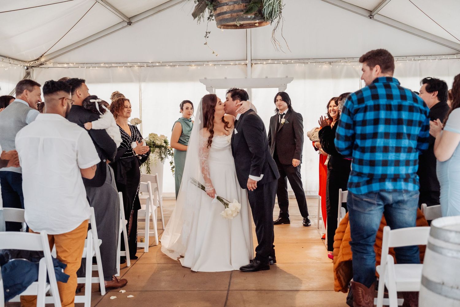 Guests dance and celebrate during a lively reception inside a white tent wedding venue.