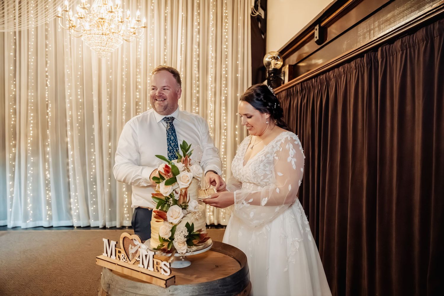 Wedding reception venue with sparkling fairy lights and brown curtain backdrop.