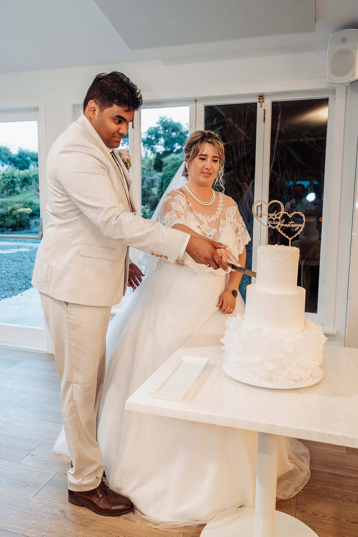 A couple cuts their elegant white wedding cake together during their reception.