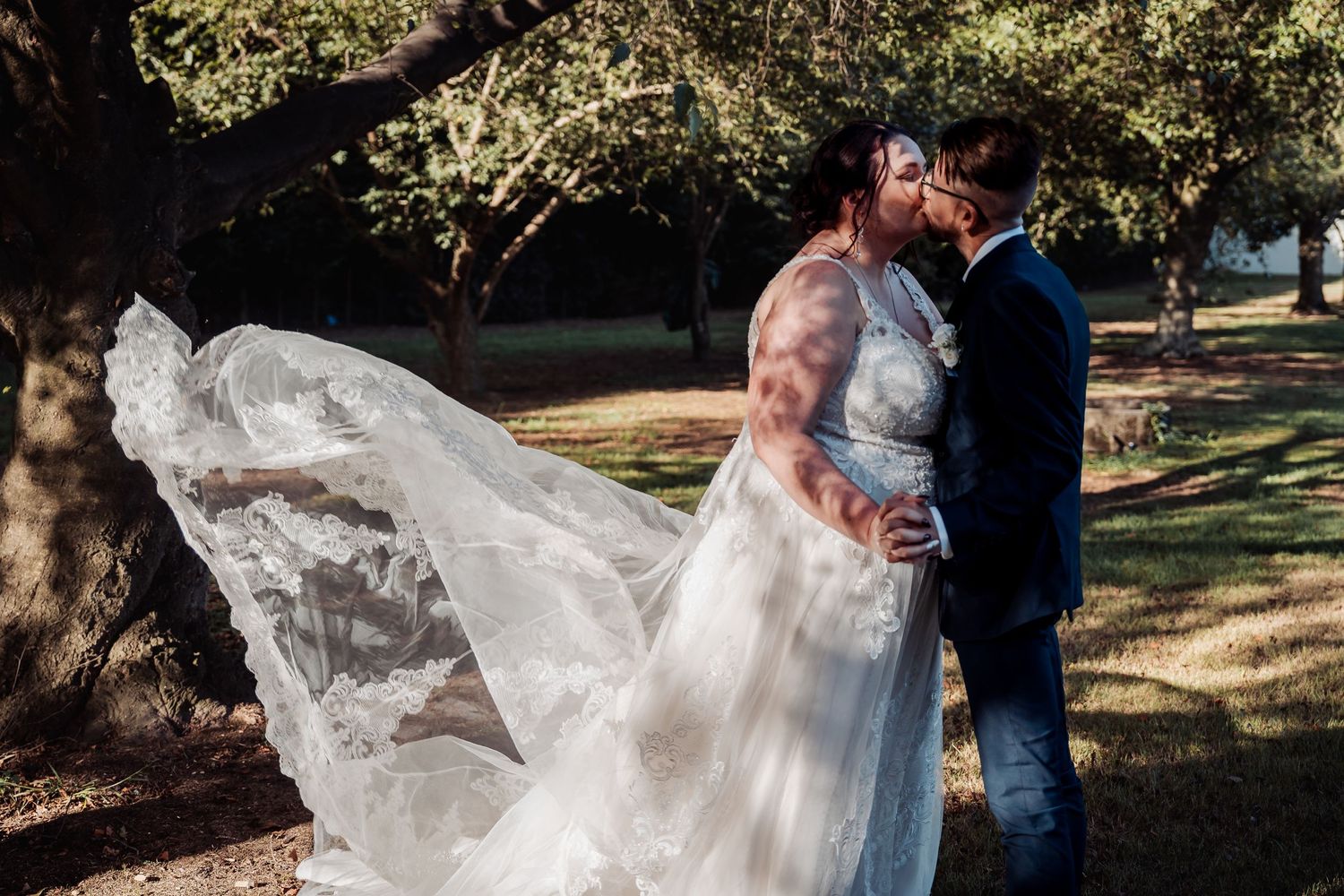 A flowing wedding dress catches the breeze during an intimate outdoor moment.